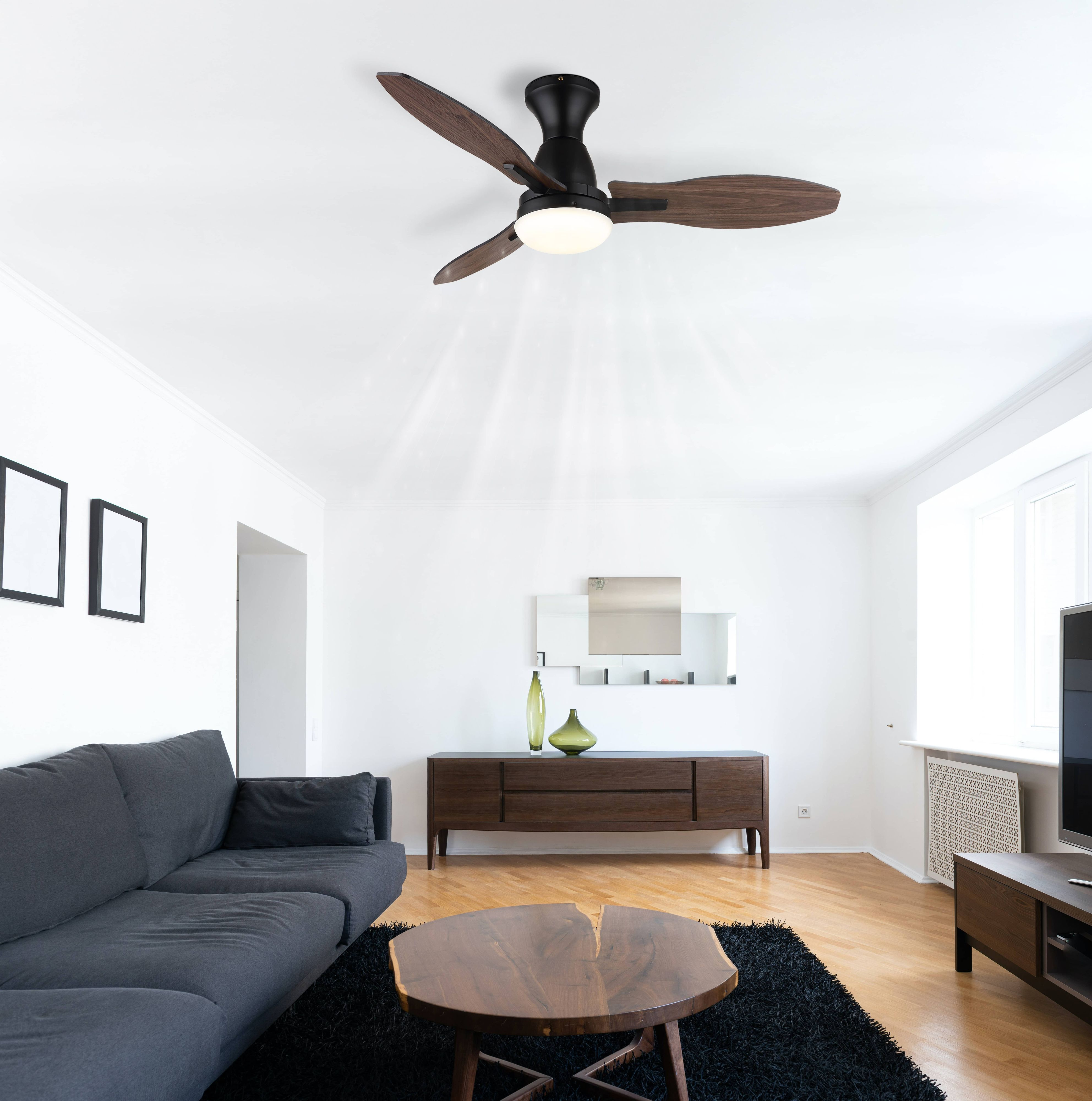 Ein modernes Wohnzimmer mit Deckenventilator, Sofa, Holztisch und Schrank. Der Raum ist gut beleuchtet und hat einen Teppich.