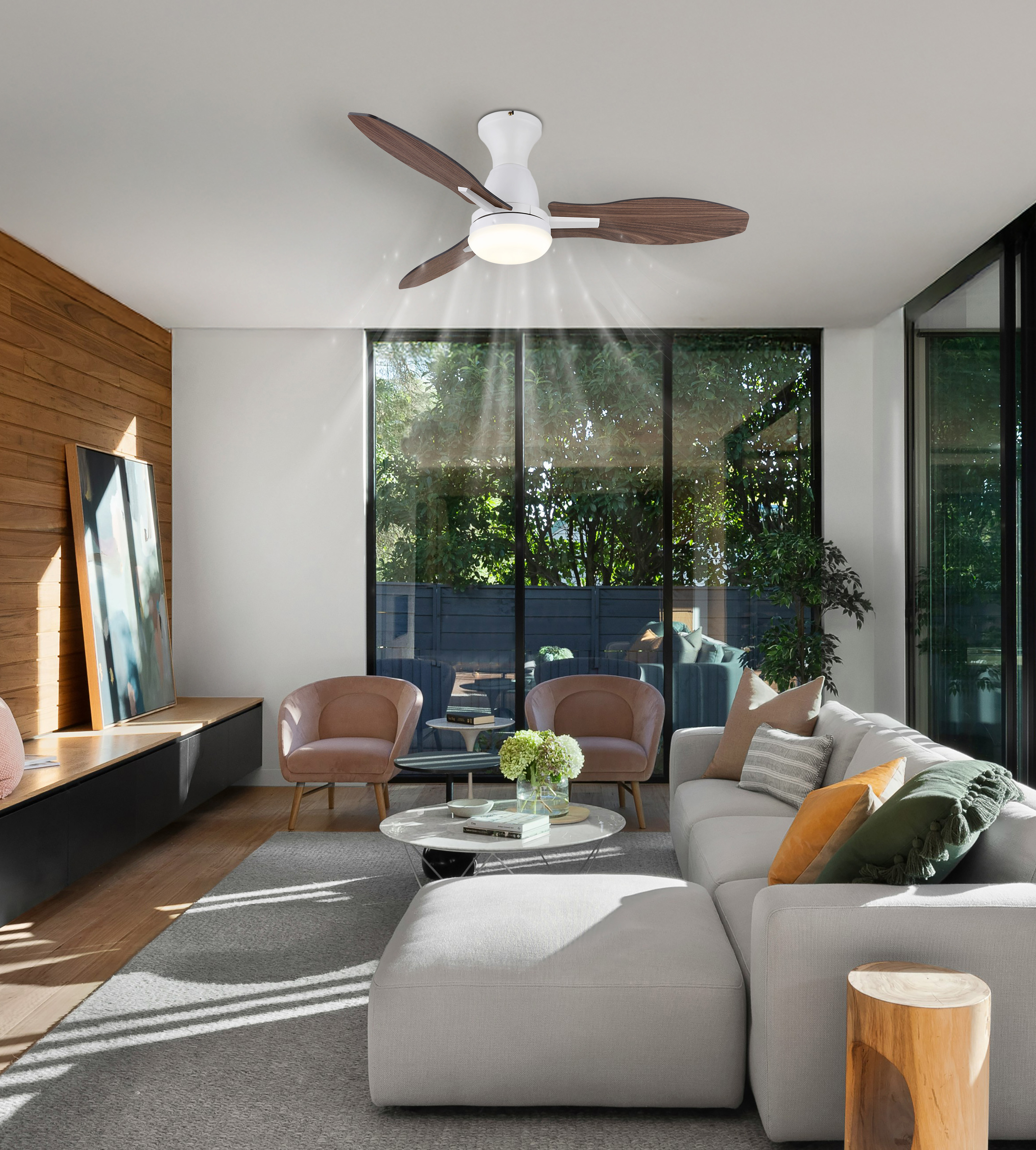 Wohnzimmer mit Deckenventilator, großen Fenstern, hellgrauem Sofa und Holzakzenten.