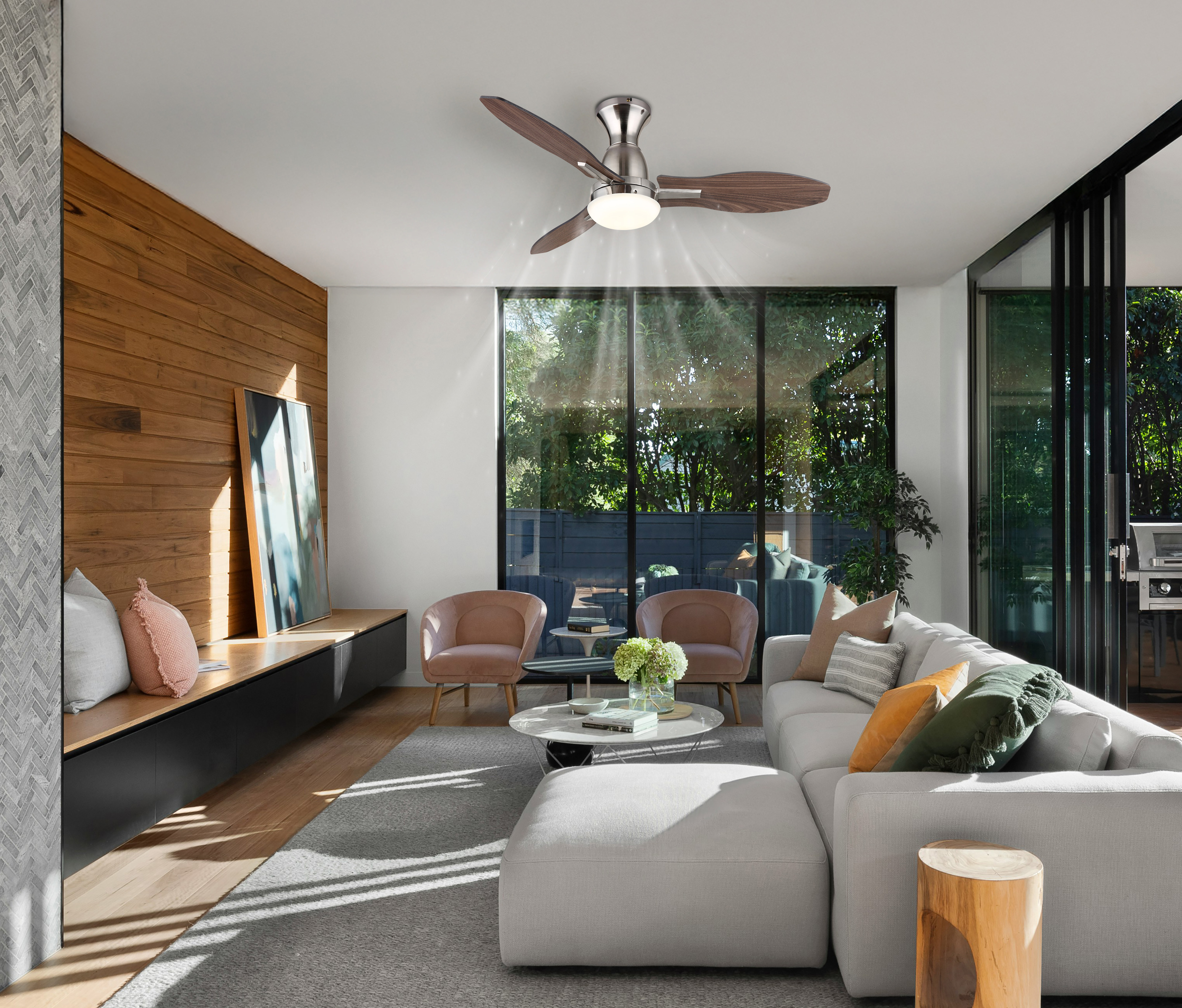 Ein modernes Wohnzimmer mit Deckenventilator, großen Fenstern, Sofa, zwei Stühlen und Holzelementen.