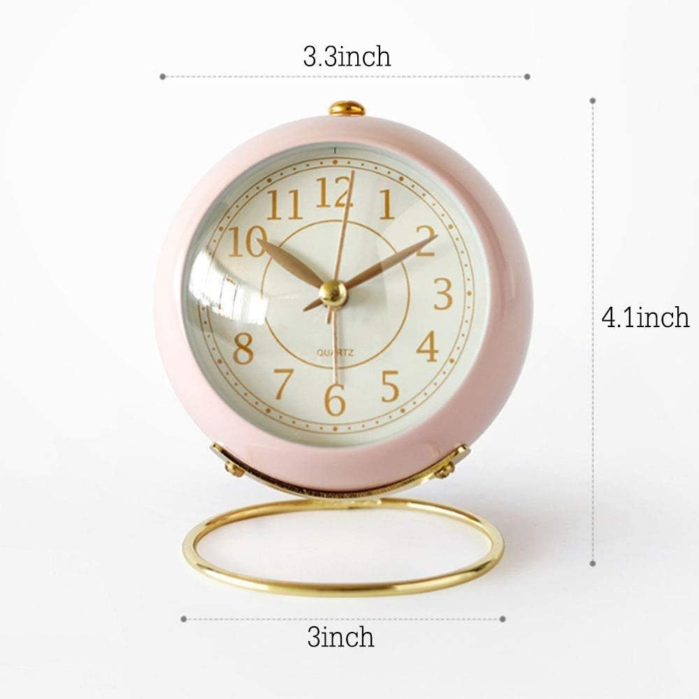 Ein rosafarbener analoger Quarz-Wecker. Er hat eine runde Form mit goldenen Zeigern und Zahlen. Die Uhr steht auf einem goldenen Ständer.