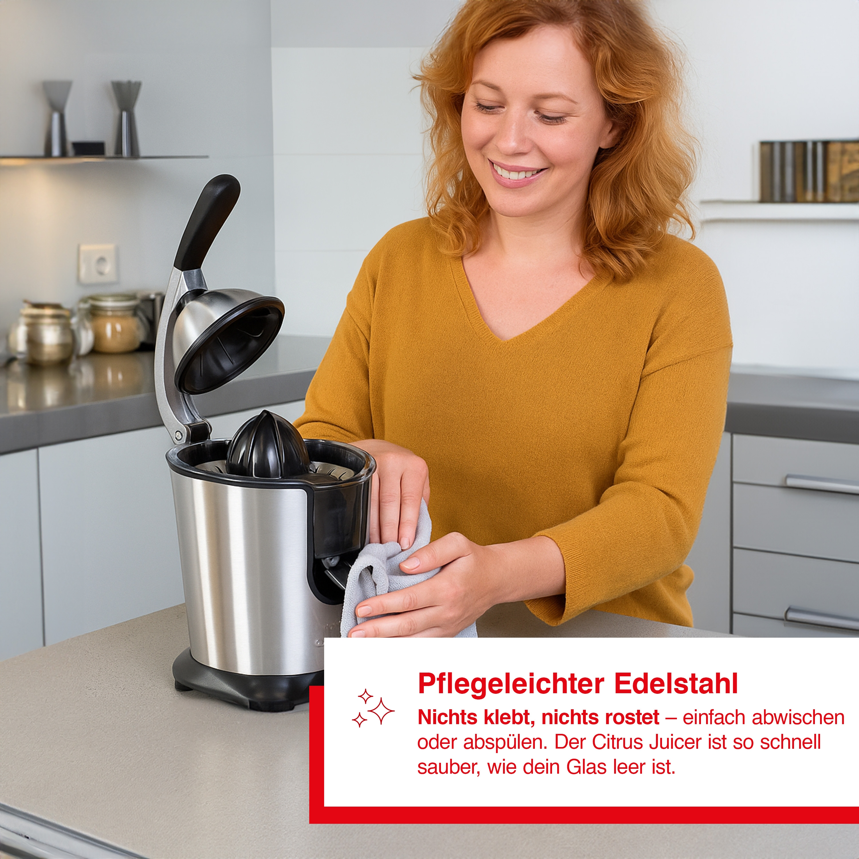 Kobieta w żółtym czyści wyciskarkę do cytrusów ze stali nierdzewnej. Wyciskarka stoi na blacie. Tło pokazuje szafki i słoiki.