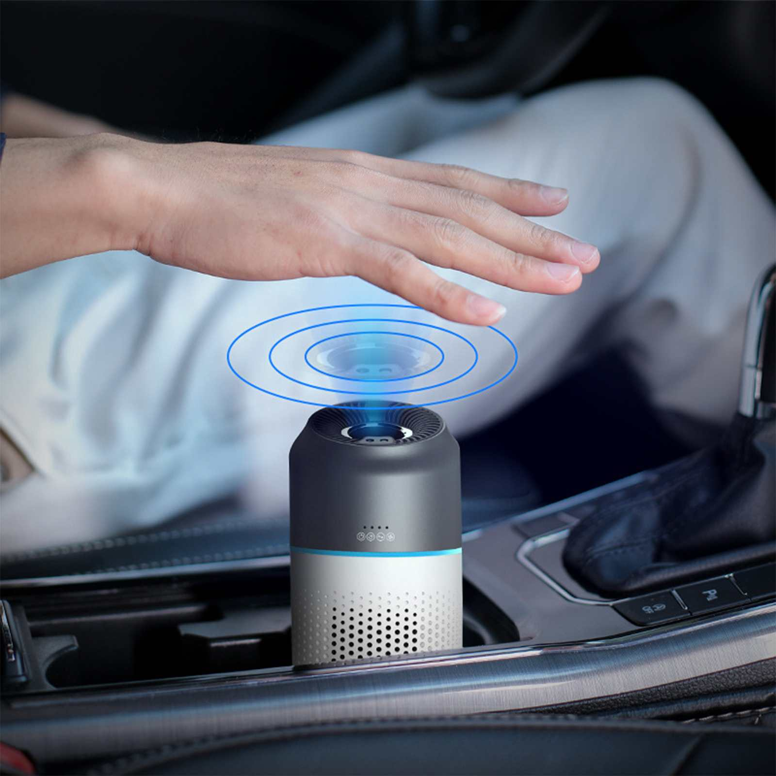 Eine Hand schwebt über einem Luftreiniger im Auto. Konzentrische blaue Kreise gehen vom Gerät aus.
