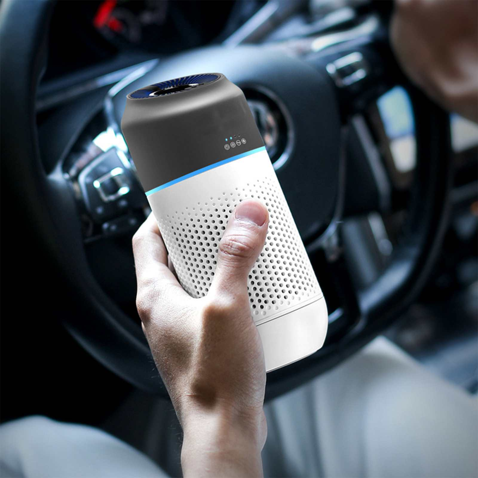 Die Hand einer Person, die einen schwarz-weißen Luftreiniger in einem Auto hält. Das Lenkrad ist im Hintergrund zu sehen.