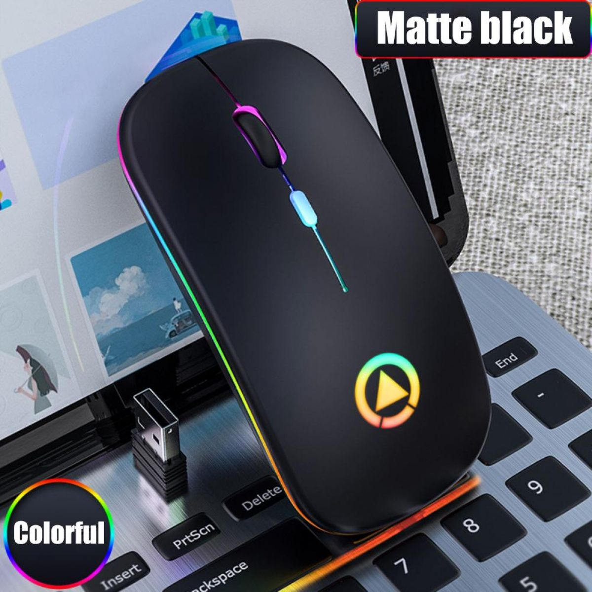 Eine mattschwarze drahtlose Maus mit farbigen LED-Akzenten liegt auf einer Laptop-Tastatur. Sie hat ein farbenfrohes Logo und einen USB-Empfänger.
