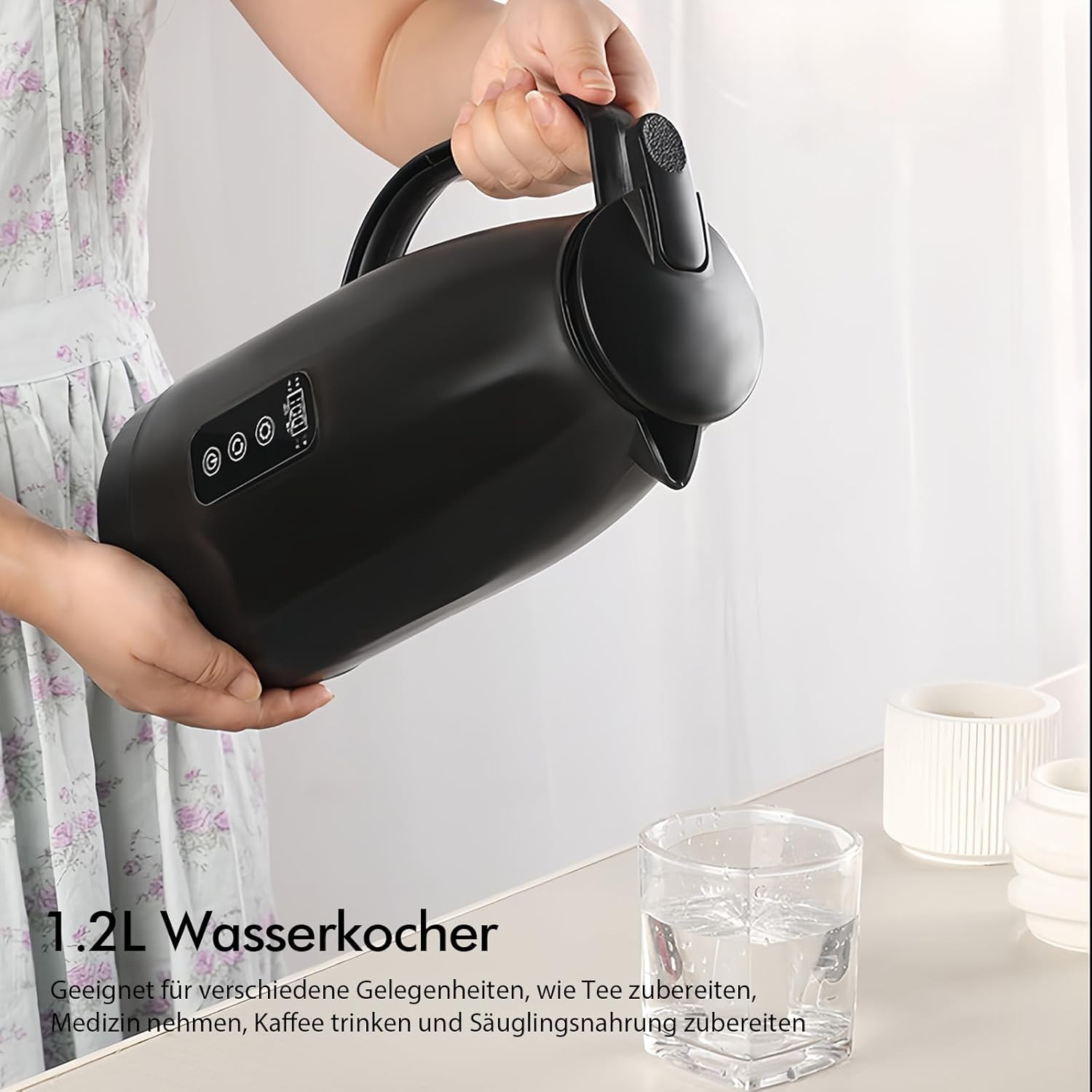 Eine Person gießt Wasser aus einem schwarzen Wasserkocher in ein Glas. Auf einem weißen Tisch stehen ein Glas und weiße Tassen.