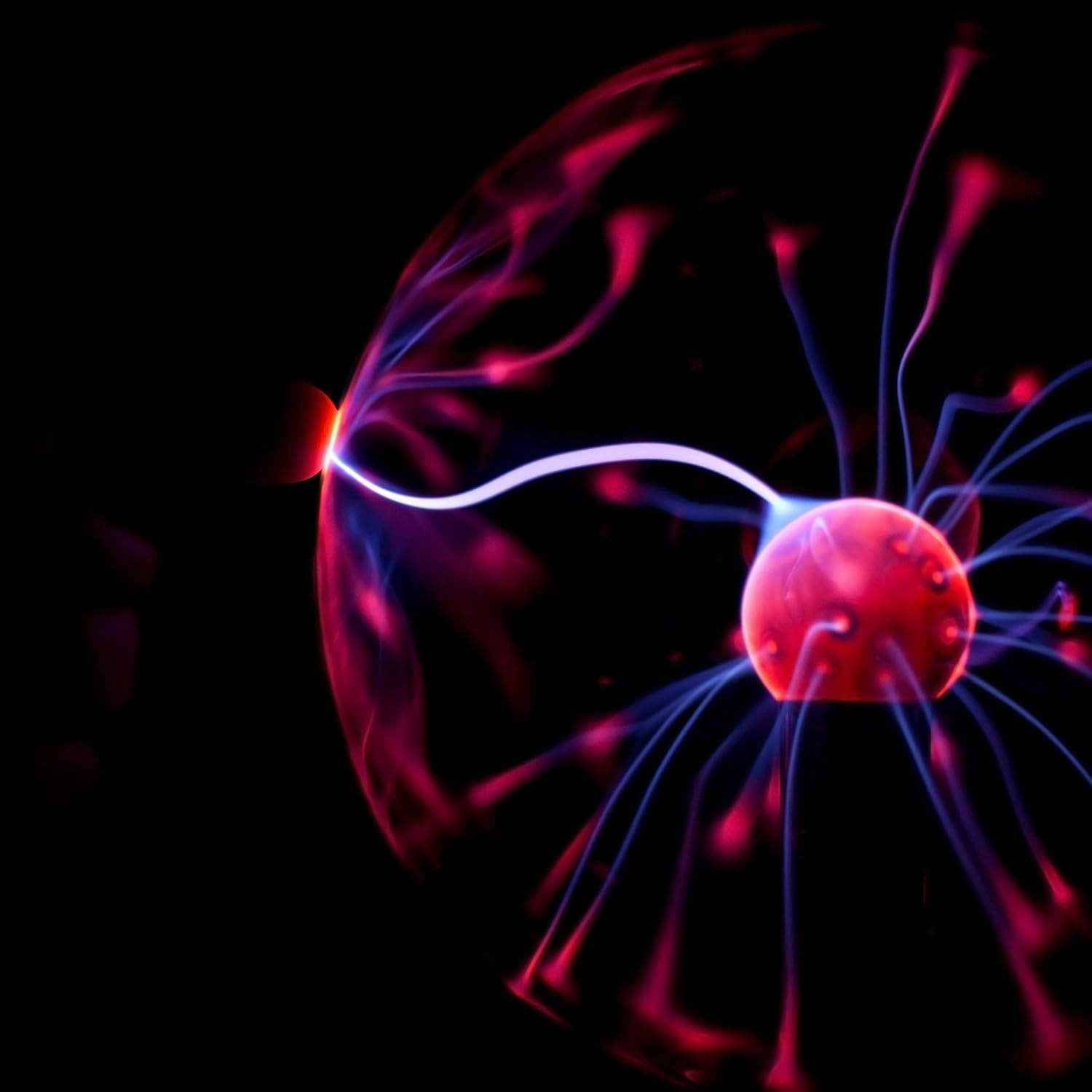 Eine Plasmakugel zeigt rote und blaue elektrische Entladungen vor schwarzem Hintergrund. Das Zentrum ist eine rote Kugel.