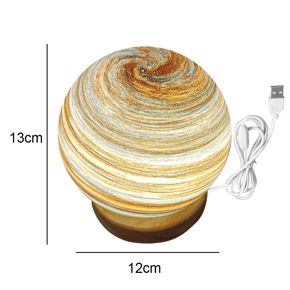 Eine kugelförmige Lampe mit Marmordesign steht auf einem Holzsockel. Ein USB-Kabel geht davon aus. Maße: 13 cm Höhe, 12 cm Breite.