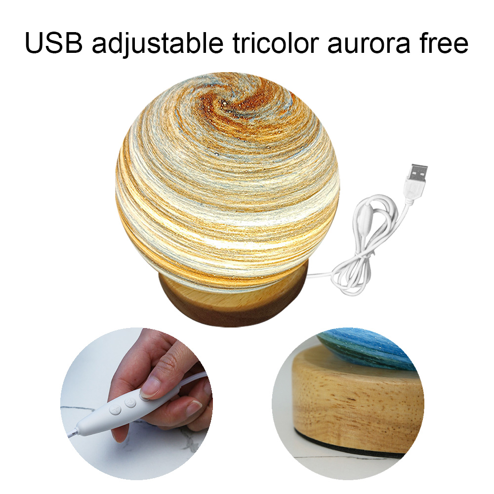 Eine dekorative Lampe mit einem kugelförmigen, wirbelnden Muster, Holzsockel und USB-Kabel. Kleine Bilder zeigen Details des Sockels und eine Hand mit einem Schalter.
