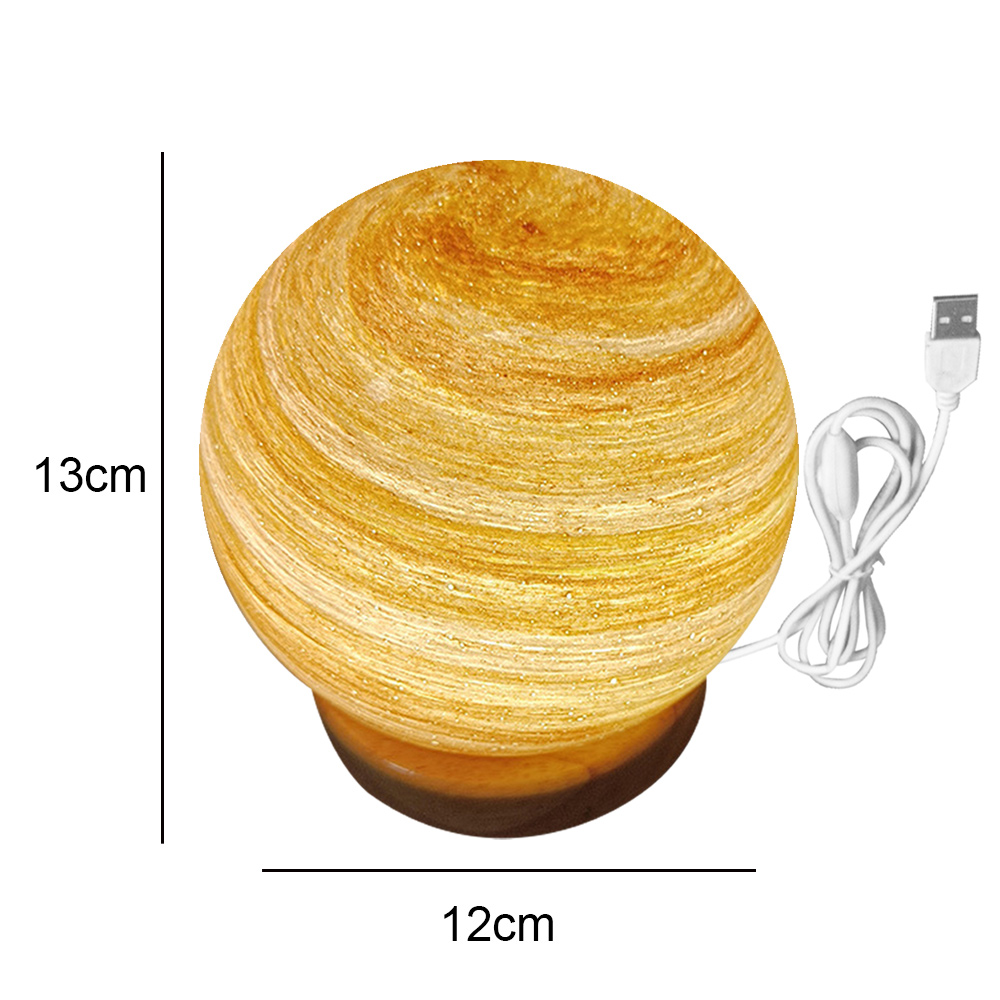 Eine kugelförmige Tischlampe mit marmoriertem gelb-braunem Design. Sie hat einen Holzsockel und ein USB-Kabel. Die Lampe ist 13 cm hoch und 12 cm breit.