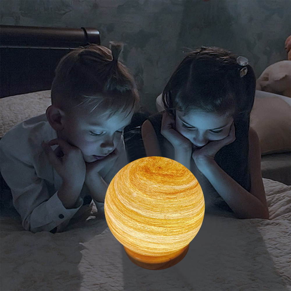 Zwei Kinder betrachten eine leuchtende Kugel auf einem Bett. Die Kugel ist gelbbraun. Der Raum ist schwach beleuchtet, was eine gemütliche Atmosphäre schafft.