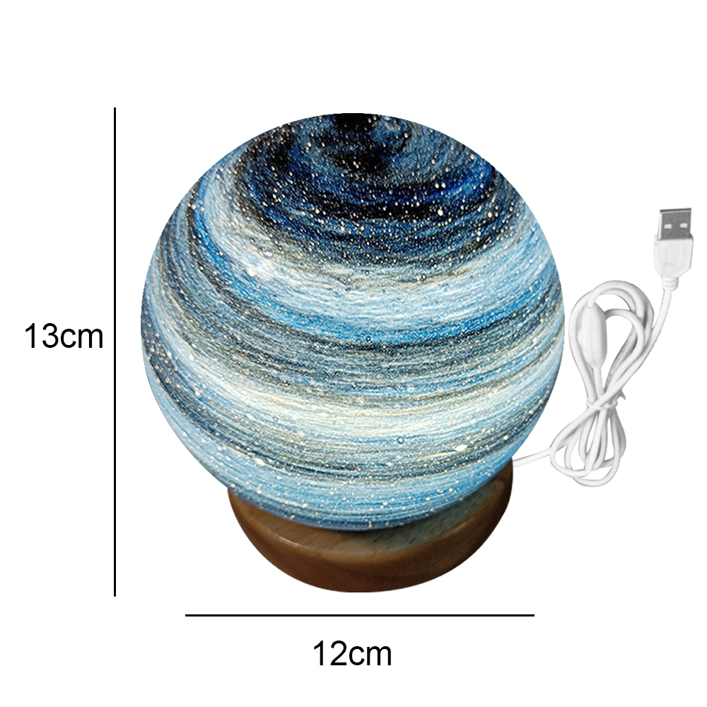 Eine kugelförmige Lampe mit blauem Galaxy-Design steht auf einem Holzsockel. Ein USB-Kabel erstreckt sich davon. Abmessungen sind 13 cm x 12 cm.