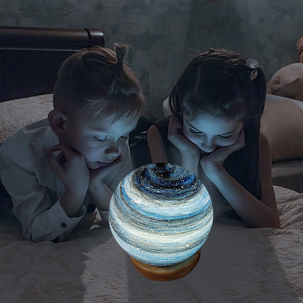 Zwei Kinder liegen auf einem Bett und betrachten eine leuchtende kugelförmige Lampe mit Galaxiedesign. Die Szene ist schwach beleuchtet.