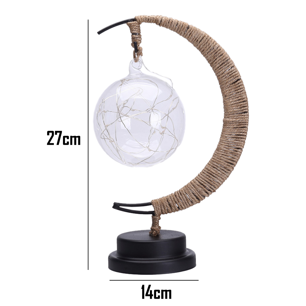 Eine dekorative Lampe mit einer Glaskugel, gefüllt mit Lichtern, getragen von einem gebogenen, seilumwickelten Rahmen auf einem schwarzen Sockel.