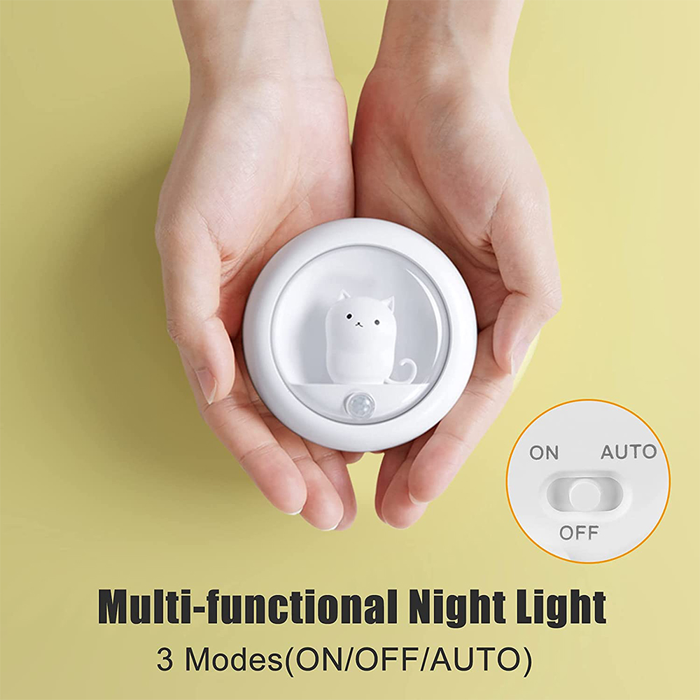 Ein weißes, katzenförmiges Nachtlicht wird in Händen gehalten. Das Licht hat einen Ein/Aus/Automatik-Schalter.