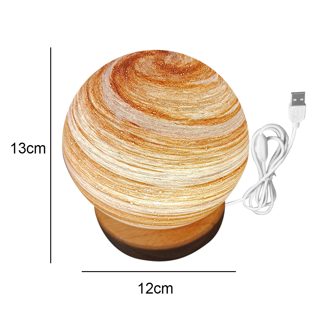 Eine dekorative Lampe mit Wirbelmuster und Holzsockel. Sie hat ein USB-Kabel und ist 13 cm hoch und 12 cm breit.