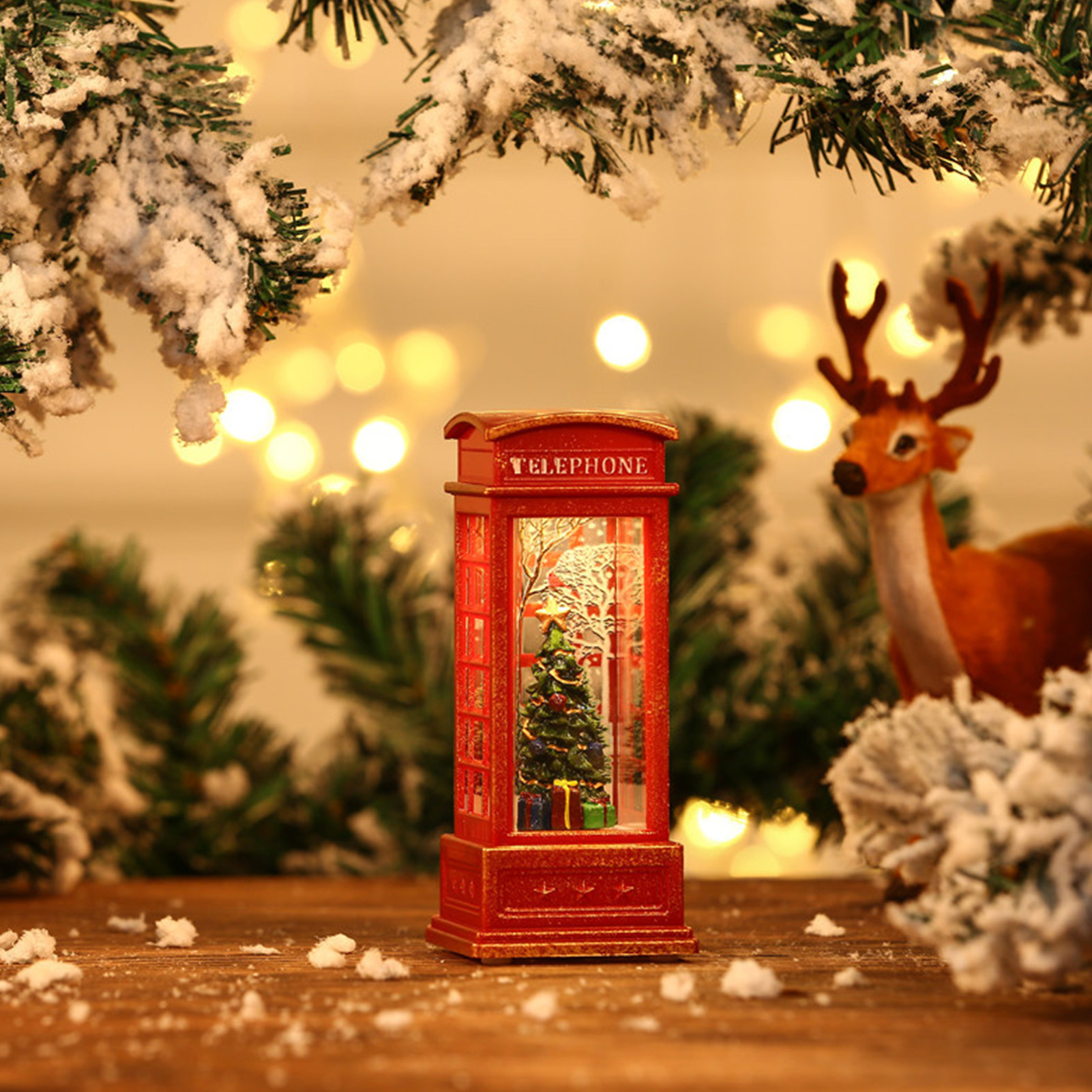 Eine rote Telefonzelle mit Weihnachtsbaum. Im Hintergrund ein Rentier und verschneite Äste.