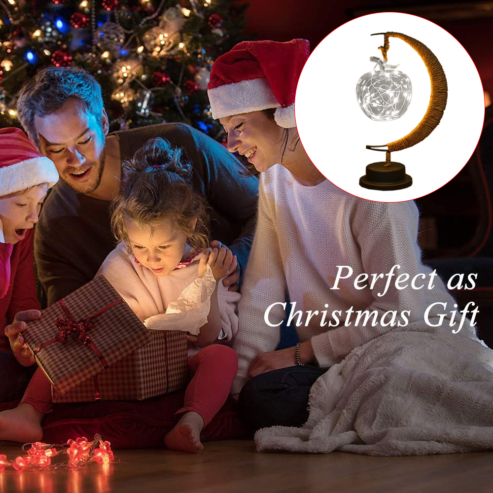 Familie öffnet Geschenk am Weihnachtsbaum. Eine dekorative Lampe in der Ecke. Text: 'Perfekt als Weihnachtsgeschenk'.