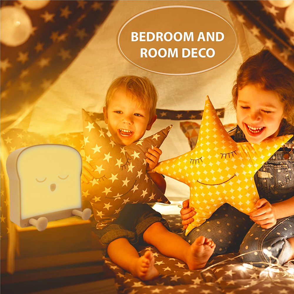 Zwei lächelnde Kinder mit Sternkissen und einer brotförmigen Lampe. Sie sitzen in einer zeltartigen Struktur mit Lichterketten.