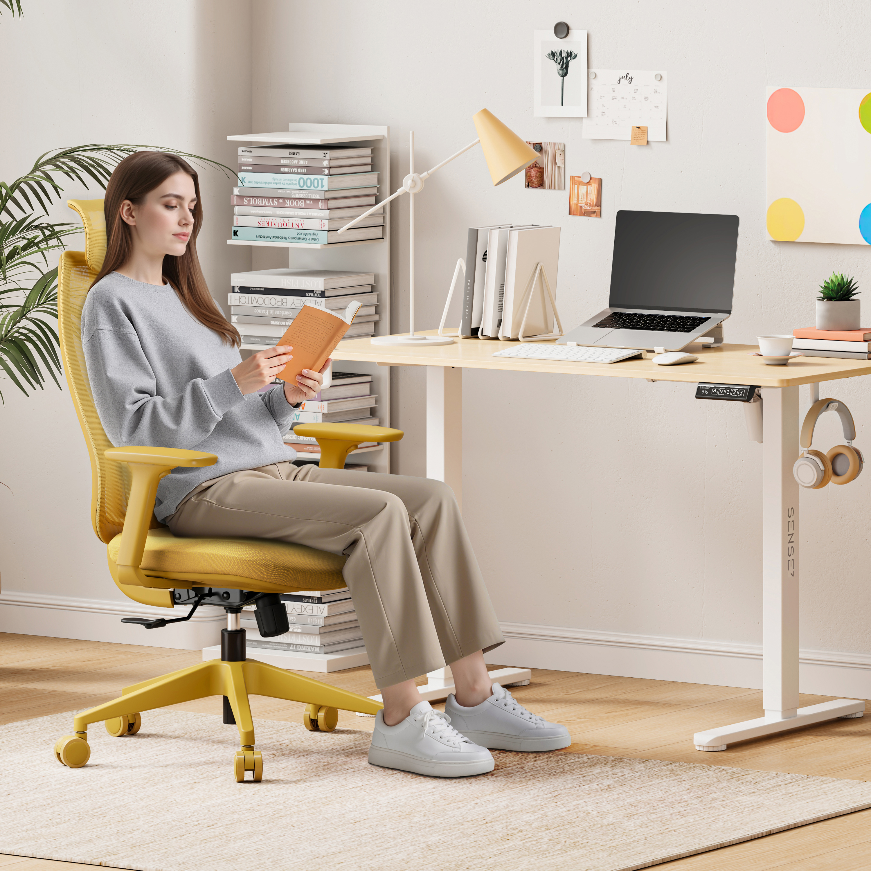 Una donna legge un libro a una scrivania. Sedia gialla, laptop, libri e lampada visibili nell'ambiente ufficio.