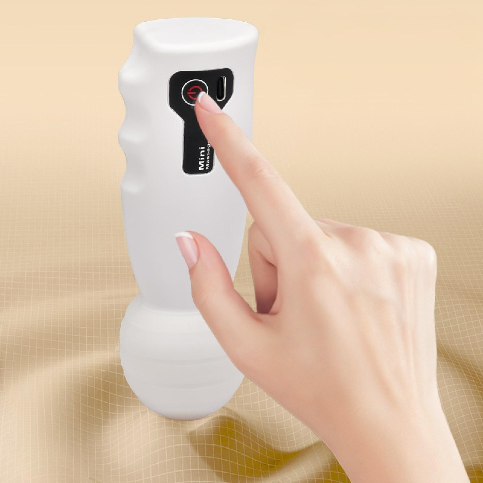 Eine Hand drückt auf eine Taste eines weißen Massagegeräts. Der Hintergrund ist ein beiger Stoff.