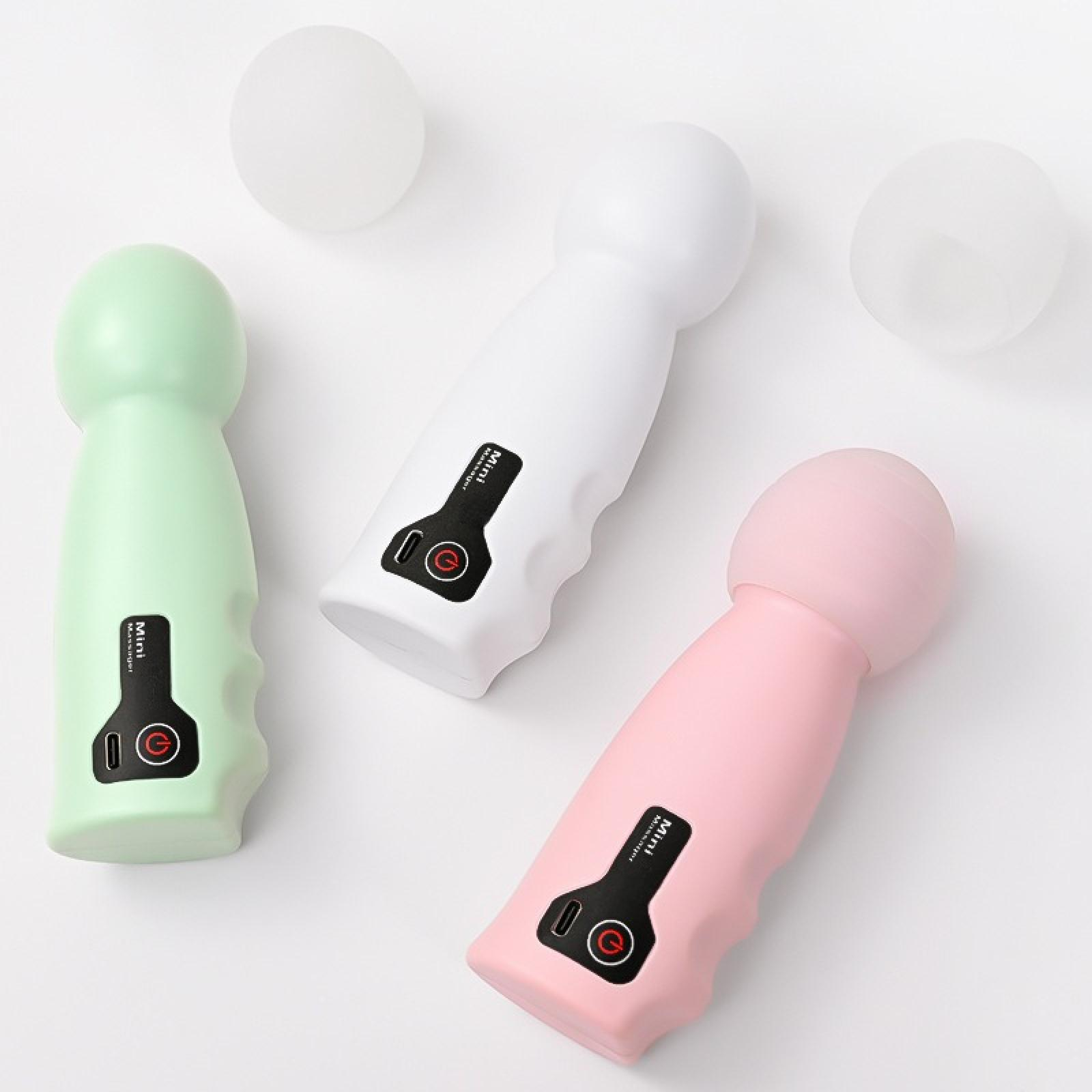 Drei Mini-Massagegeräte: grün, weiß und rosa. Jedes hat einen Ein-/Ausschalter. Zwei weiße Kugeln im Hintergrund auf weißem Untergrund.