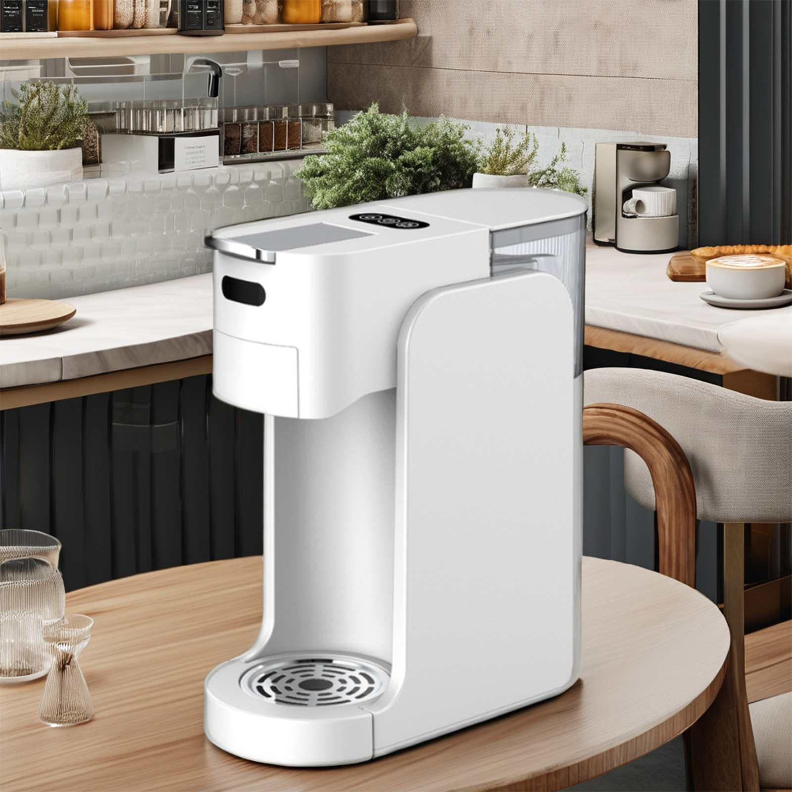 Eine weiße Kaffeemaschine steht auf einem Tisch. Im Hintergrund eine Küchenzeile mit Gewürzen und Pflanzen.