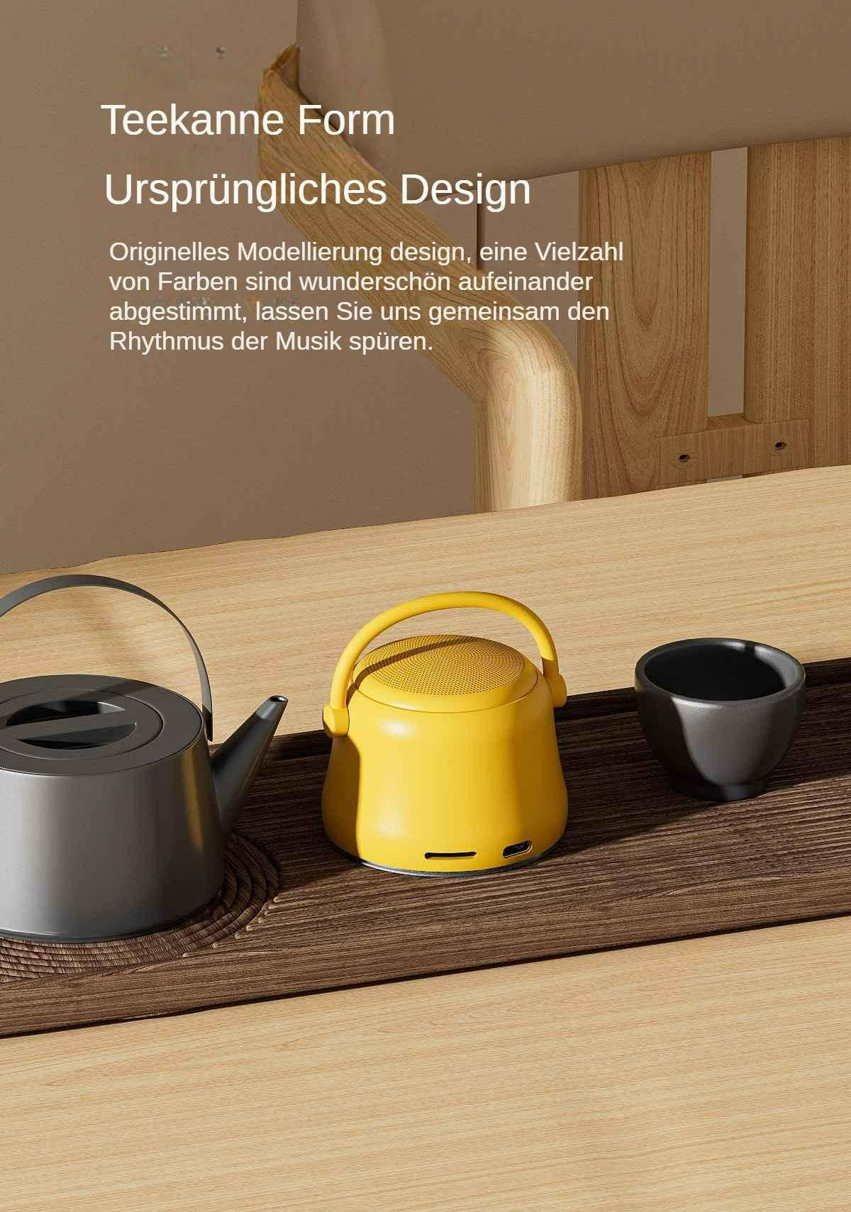 Ein gelbes Audiogerät, eine graue Teekanne und eine schwarze Tasse stehen auf einem Holztisch mit einer braunen Matte; Text auf Deutsch.