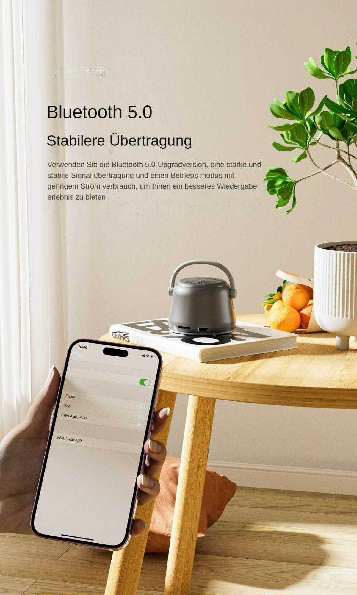 Eine Hand hält ein Telefon mit Bluetooth-Einstellungen. Ein Lautsprecher und Obst stehen auf einem Tisch mit einer Pflanze.