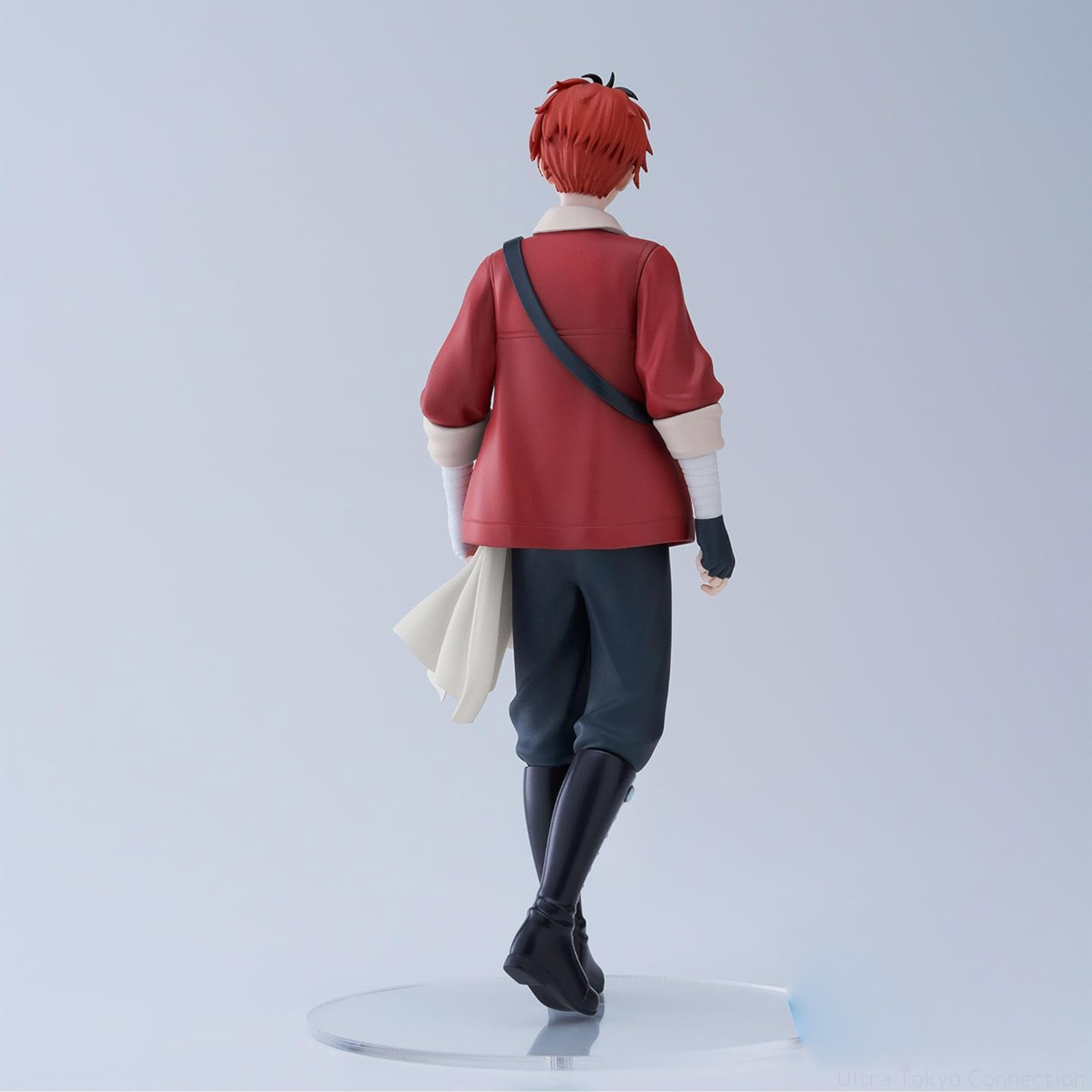 Figur eines Mannes in roter Jacke, schwarzer Hose und Stiefeln. Er hat rotes Haar und hält ein weißes Tuch. Von hinten gesehen.