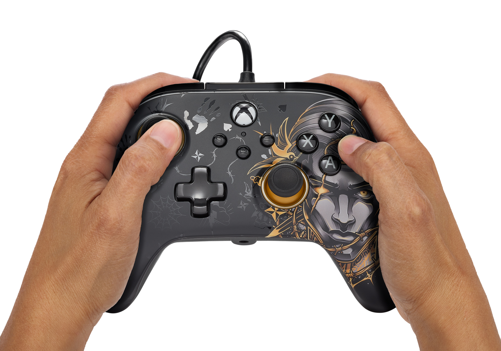 Ręce trzymające czarny kontroler Xbox z unikalnym designem. Kontroler ma grafikę twarzy i kabel.