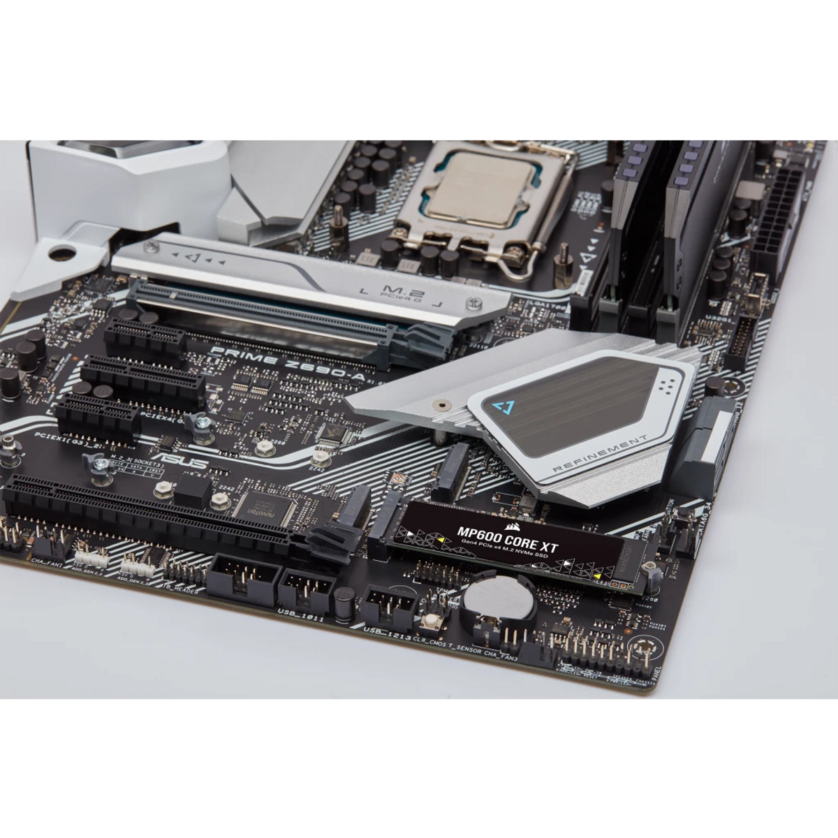 Płyta główna komputera z różnymi komponentami, takimi jak CPU, gniazda RAM i gniazdo M.2 oraz czarna karta SSD.