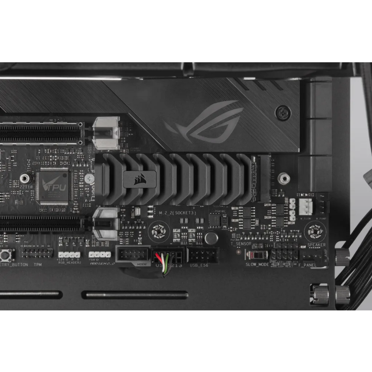 Zbliżenie czarnej płyty głównej komputera. Widoczne są komponenty takie jak procesor, radiator Corsair i różne złącza.