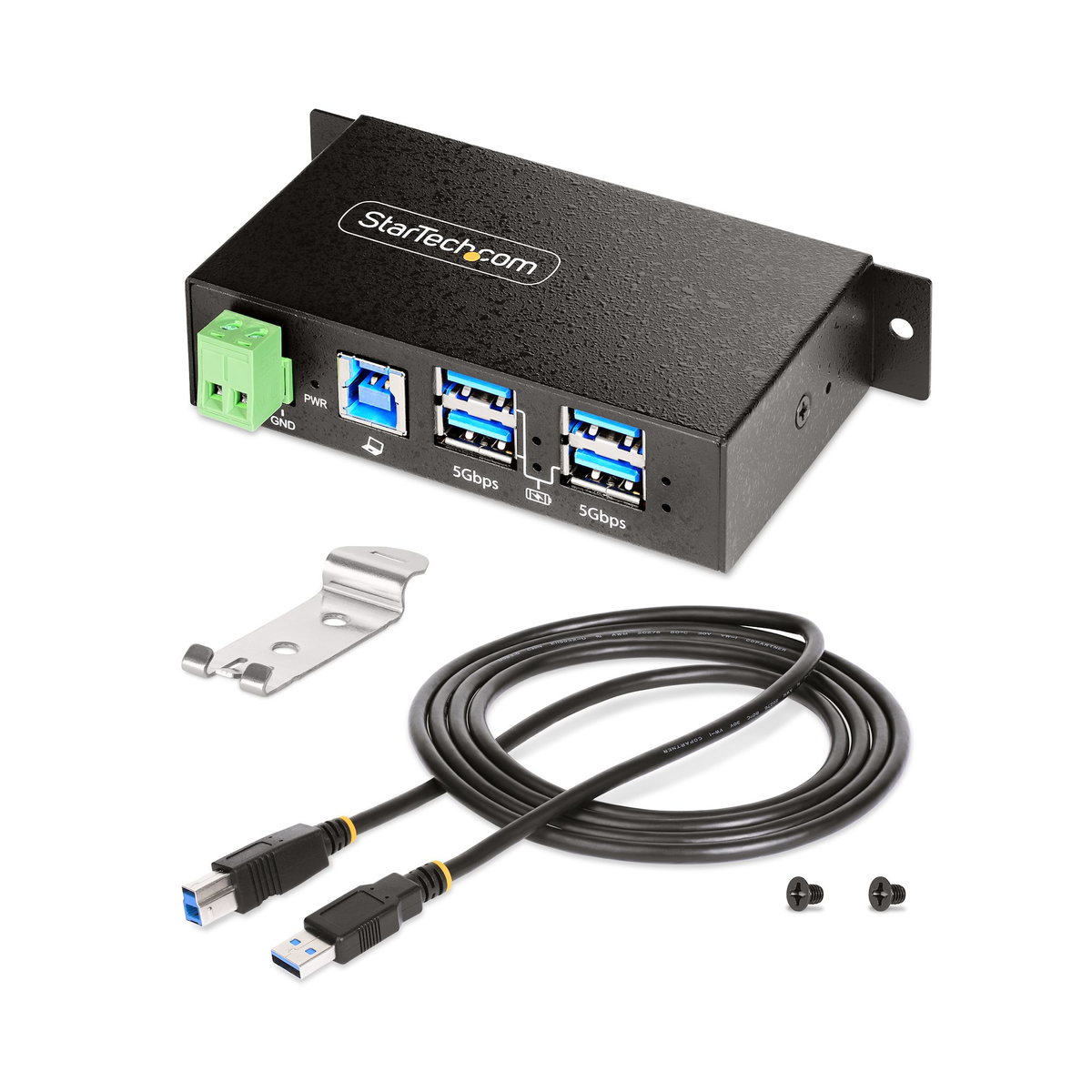 Un concentrador USB StarTech negro con puertos, cables, un soporte y tornillos sobre una superficie blanca. Tiene un conector de alimentación verde.