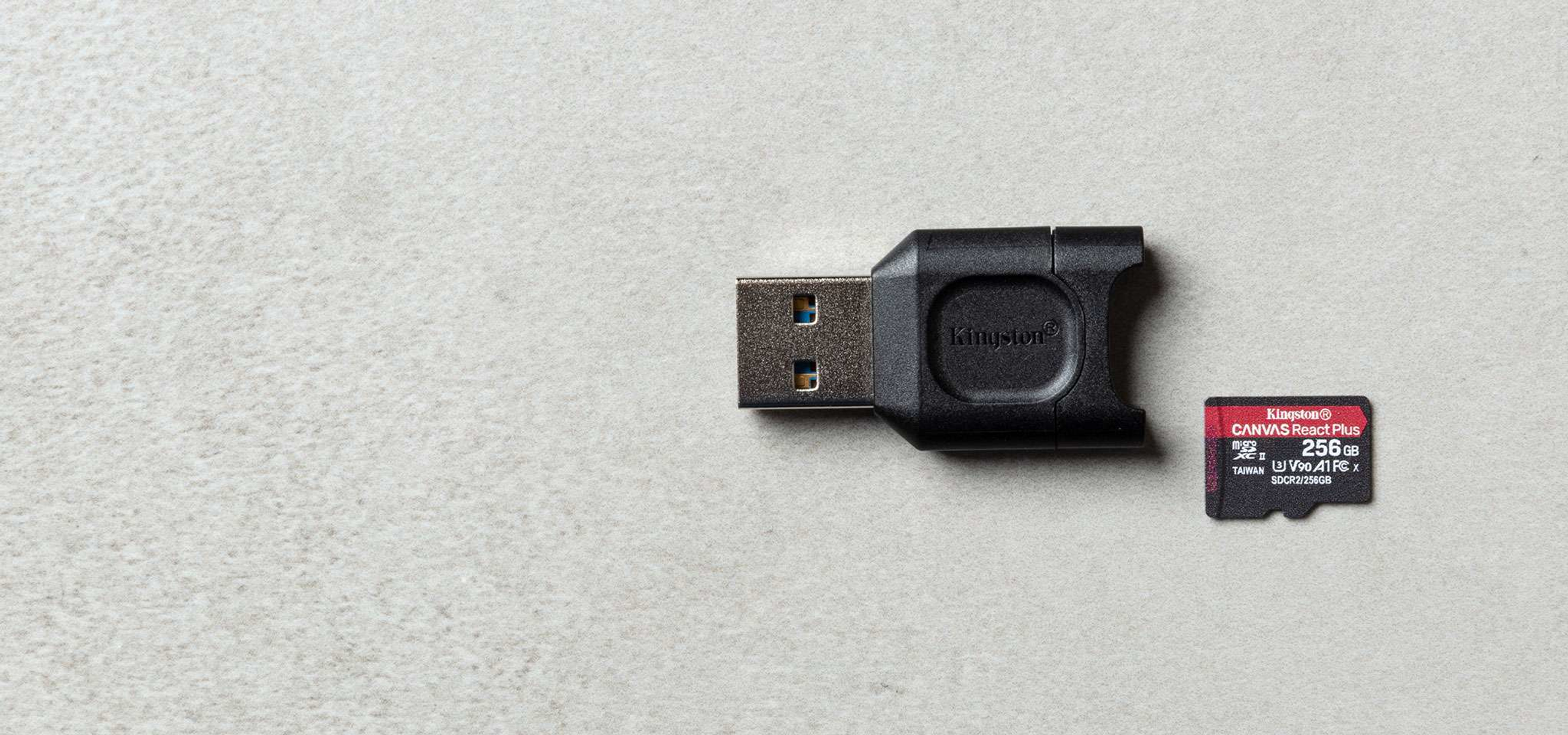 Dysk USB i karta micro SD na jasnoszarej powierzchni. Karta SD jest oznaczona jako Kingston CANVAS React Plus.