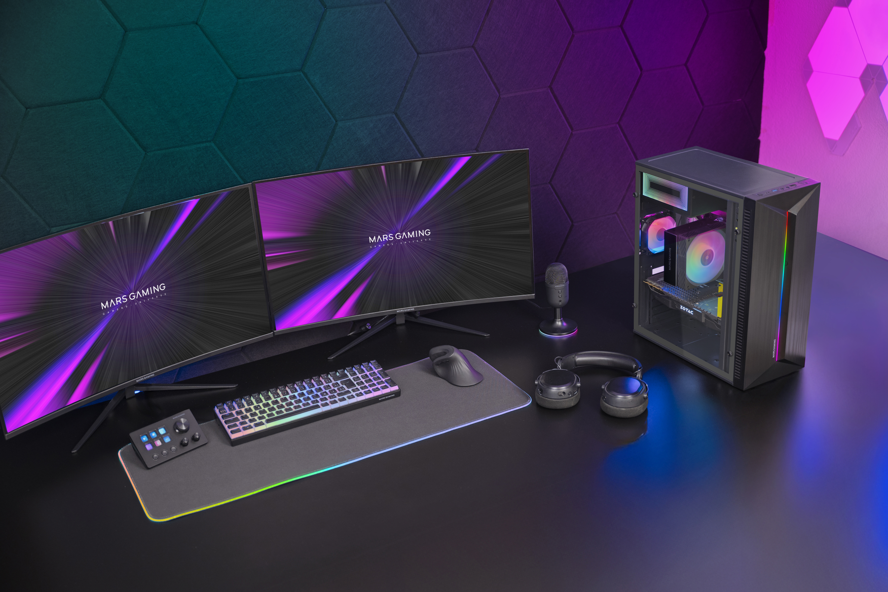 Un'impostazione di gioco con tre monitor, PC, tastiera, mouse, microfono, cuffie e un pannello di controllo. Tutto con illuminazione RGB.