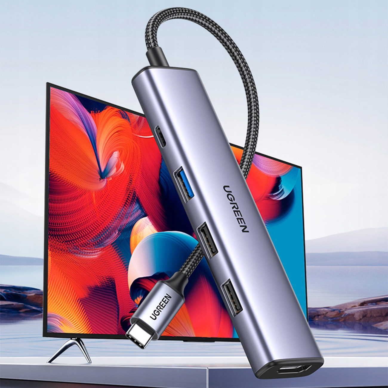 Hub USB UGREEN z wieloma portami, podłączony do ekranu. Hub jest srebrny i czarny, z widocznym logo UGREEN.