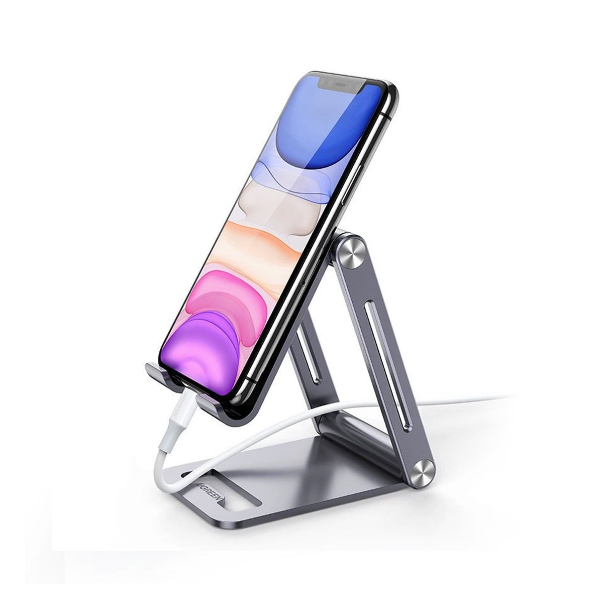 Smartfon na srebrnym stojaku z białym kablem ładującym. Telefon wyświetla fioletową i niebieską tapetę.