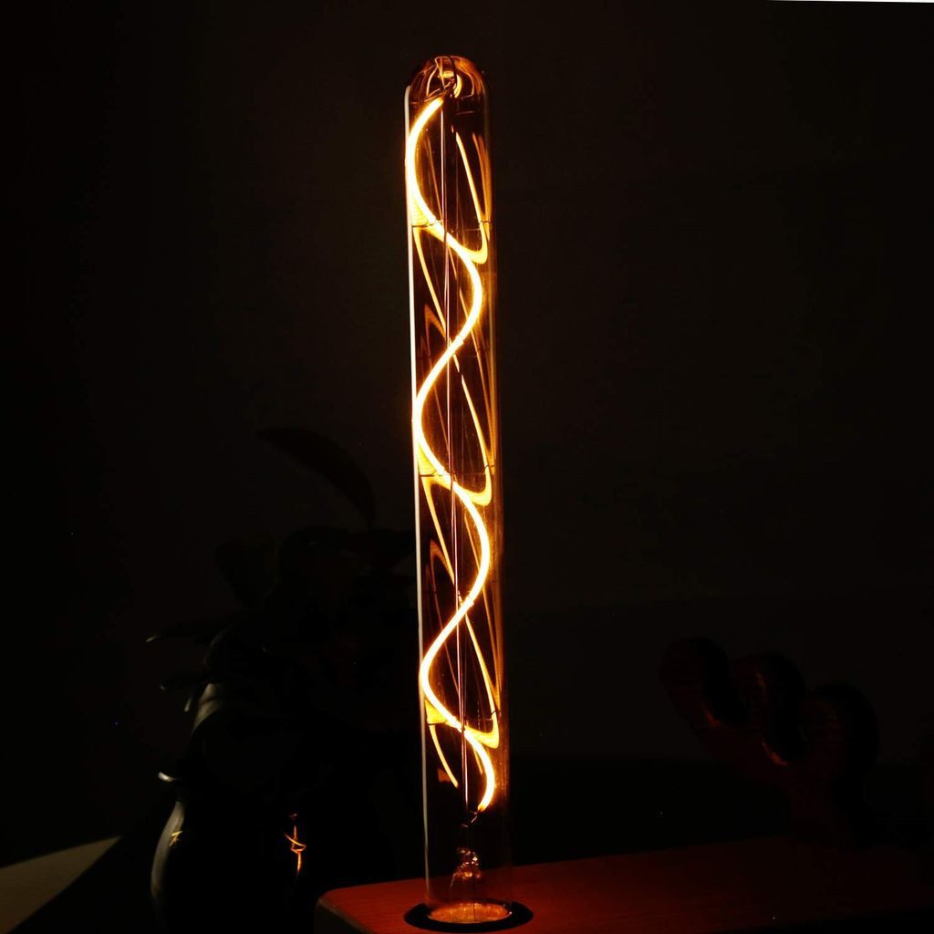 Pionowa, świecąca żarówka z spiralnym żarnikiem. Znajduje się w ciemnym otoczeniu, na drewnianej powierzchni.