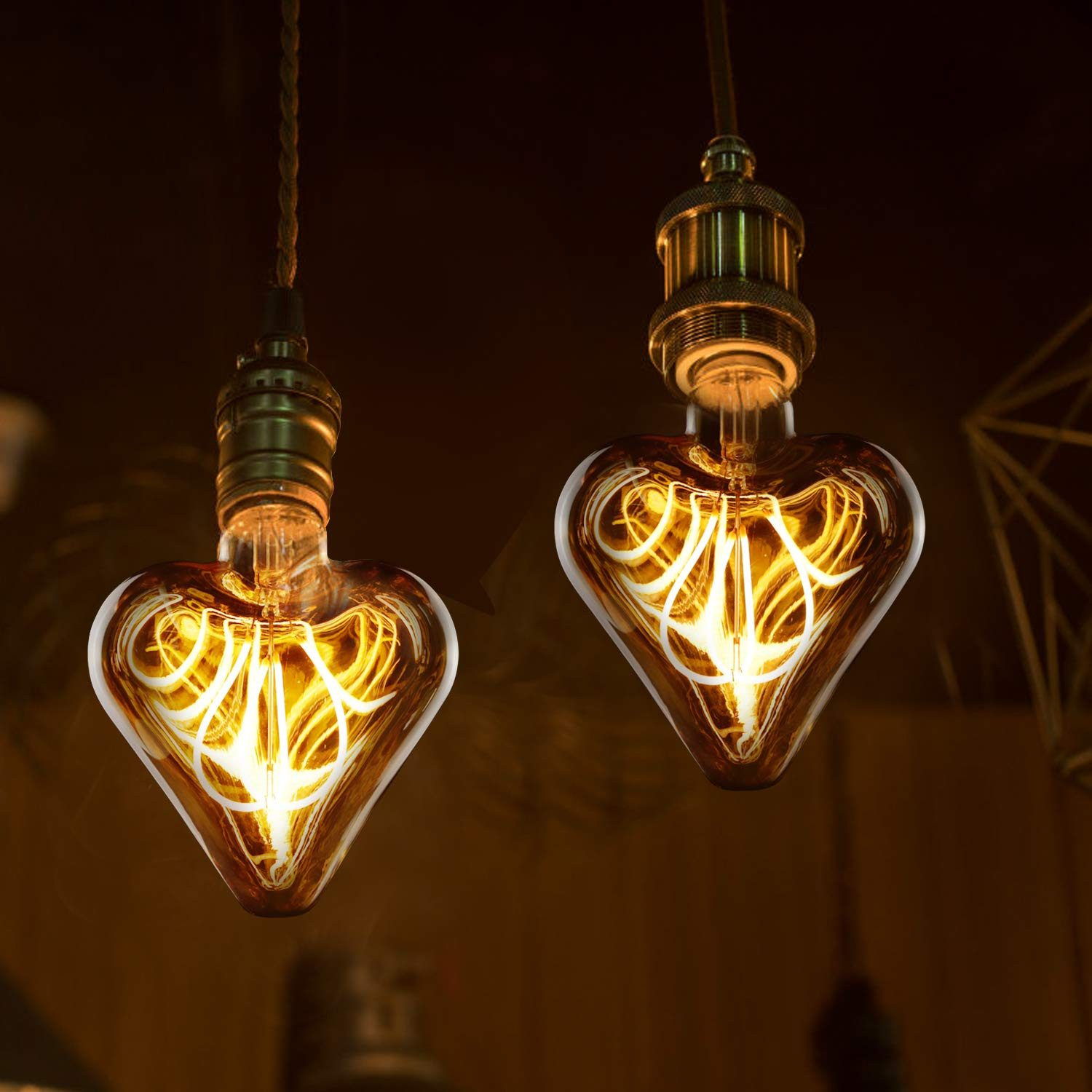 Dwie żarówki w kształcie serca zwisają z sufitu. Mają ciepłą, żółtą poświatę i skomplikowane wewnętrzne włókna, tworząc romantyczną atmosferę.