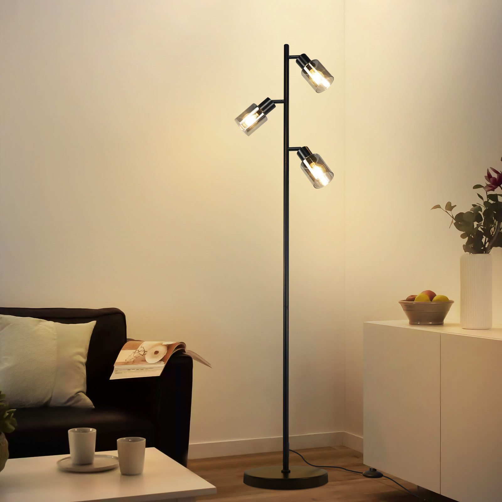 Nowoczesny salon z czarną lampą podłogową, sofą, stolikiem kawowym i szafką. Obecne są owoce i kwiaty.