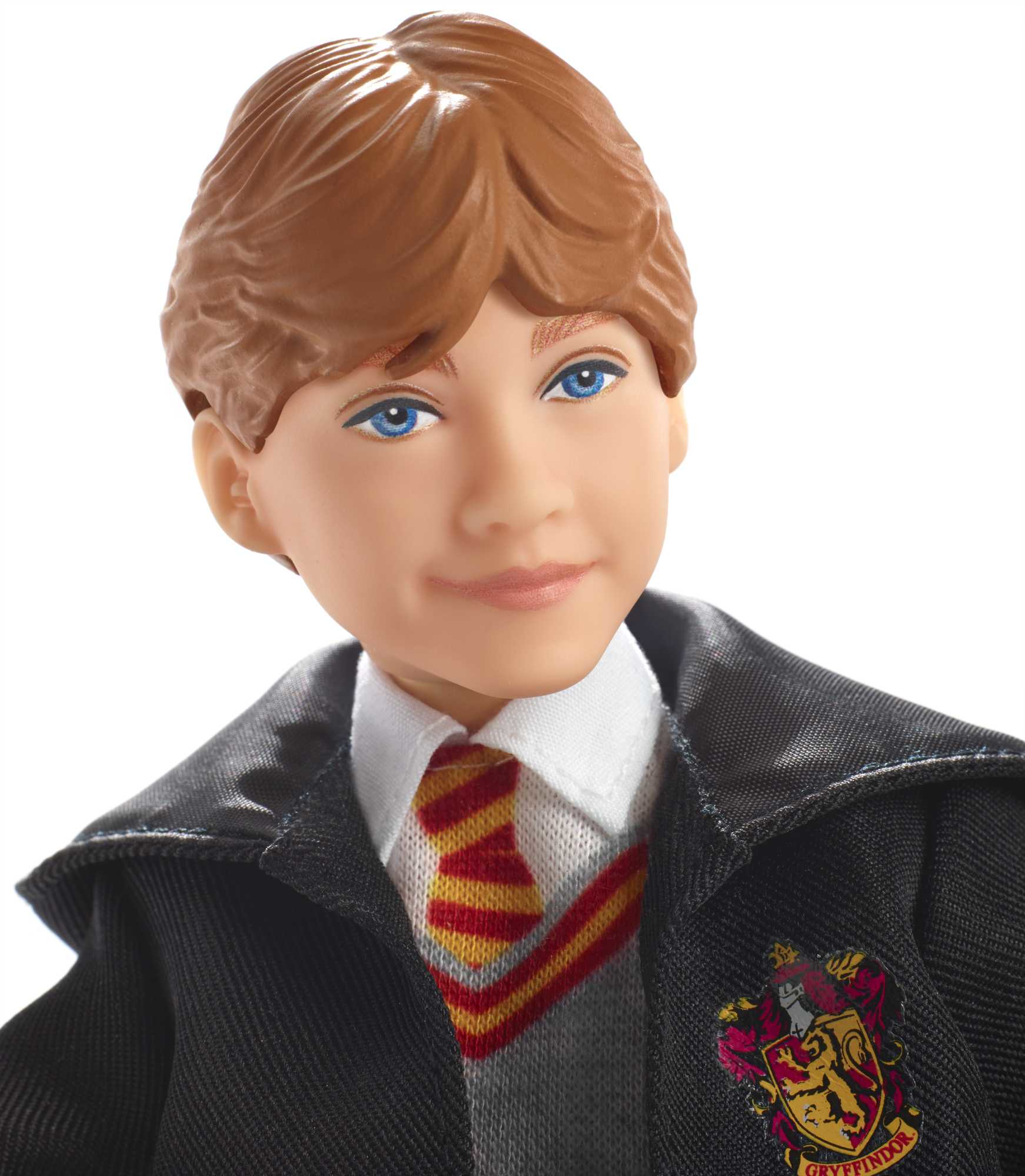 Eine Puppe eines jungen Mannes mit braunen Haaren, blauen Augen und einer Gryffindor-Uniform, der auf weißem Hintergrund lächelt.