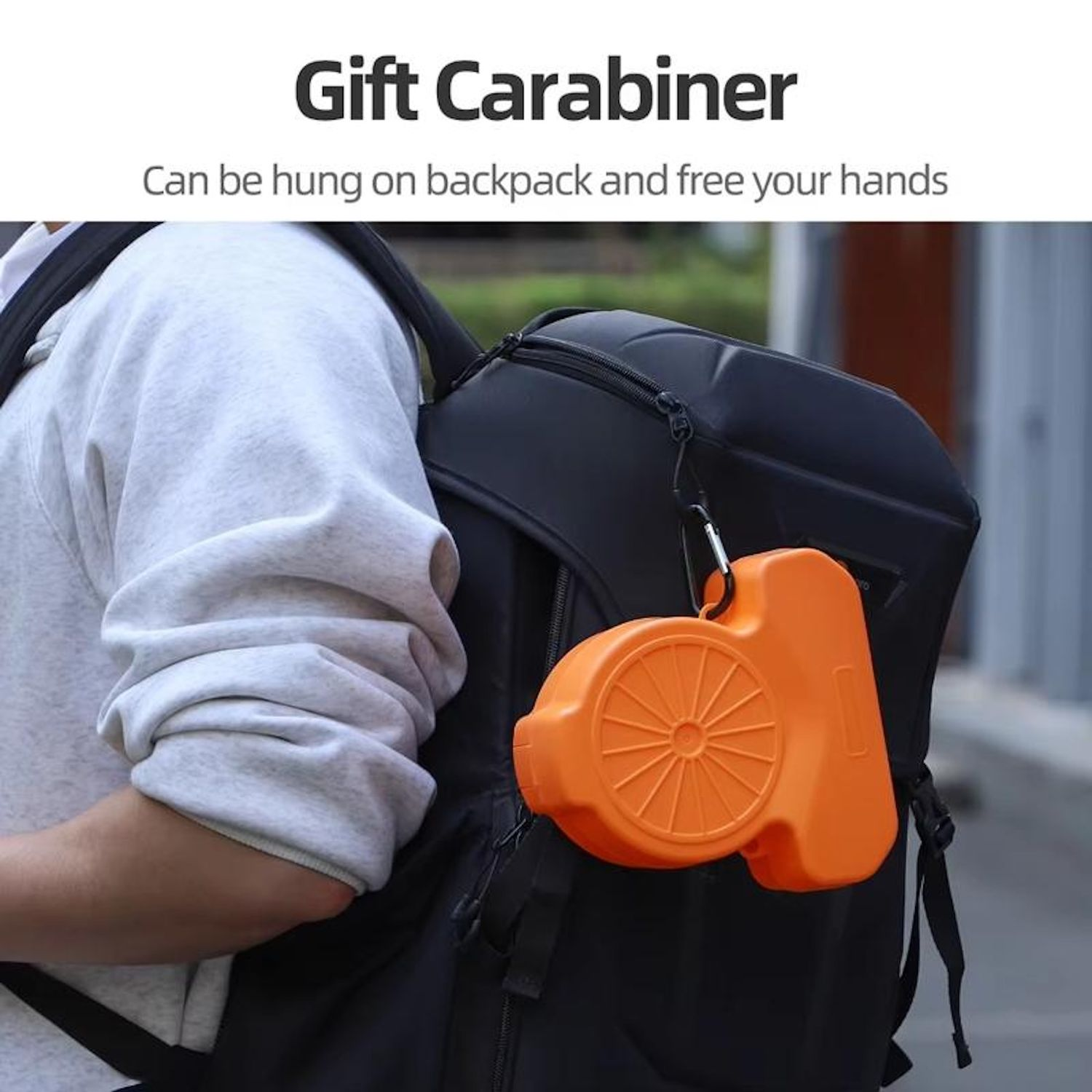 Ein orangefarbener Geschenk-Karabiner ist an einem schwarzen Rucksack befestigt. Der Rucksack befindet sich auf dem Rücken einer Person.