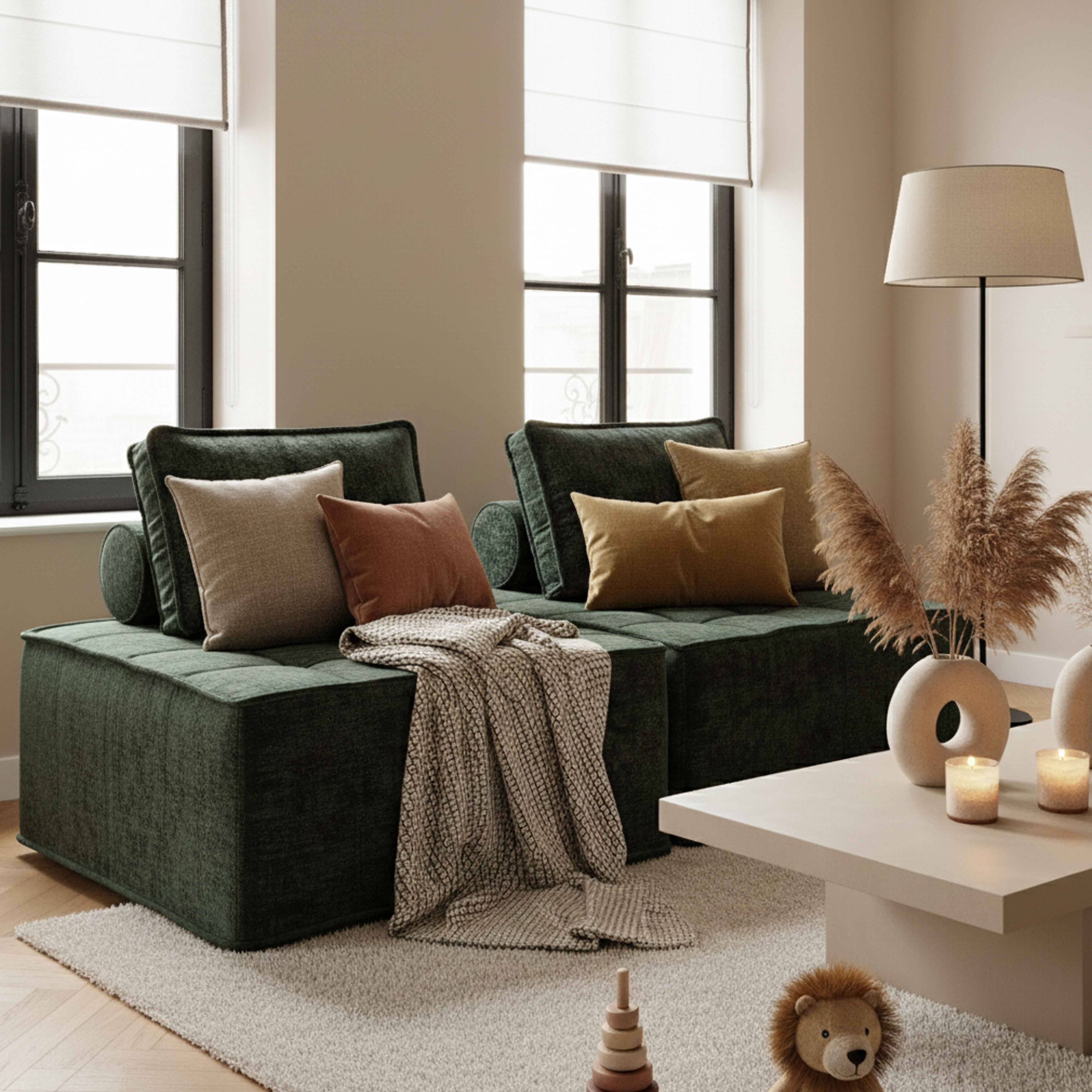 Wohnzimmer mit grünem Sofa, Kissen, Decke, Couchtisch mit Kerzen und Dekoration und zwei Fenstern.