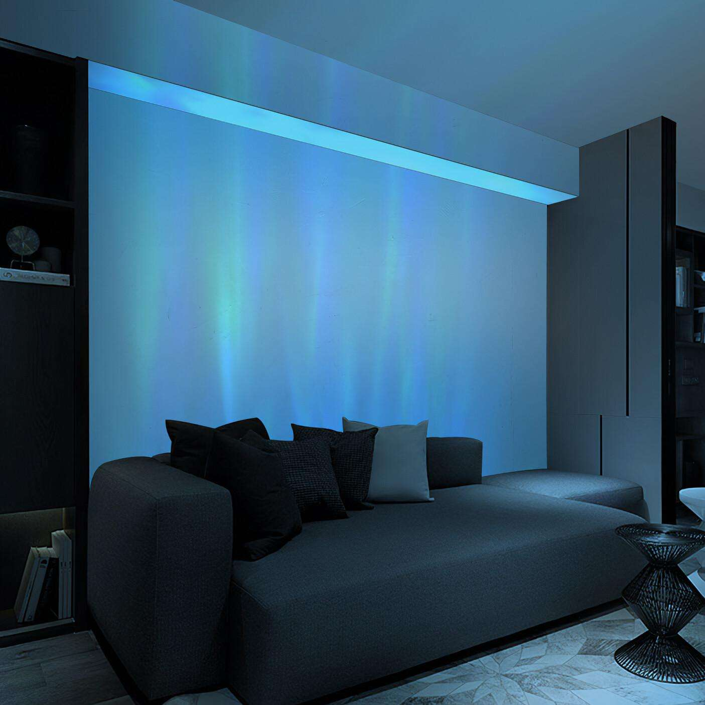 Ein modernes Wohnzimmer mit grauem Sofa und Kissen. Die Wand ist mit blauen Lichtern beleuchtet, die einem Nordlicht ähneln. Ein schwarzer Beistelltisch ist vorhanden.