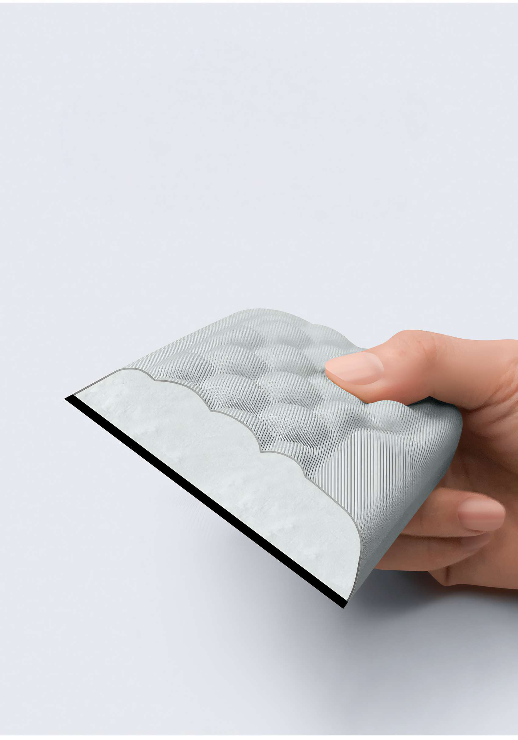 Eine Hand hält ein grau strukturiertes Objekt mit schwarzem Rand. Der Hintergrund ist schlicht weiß.