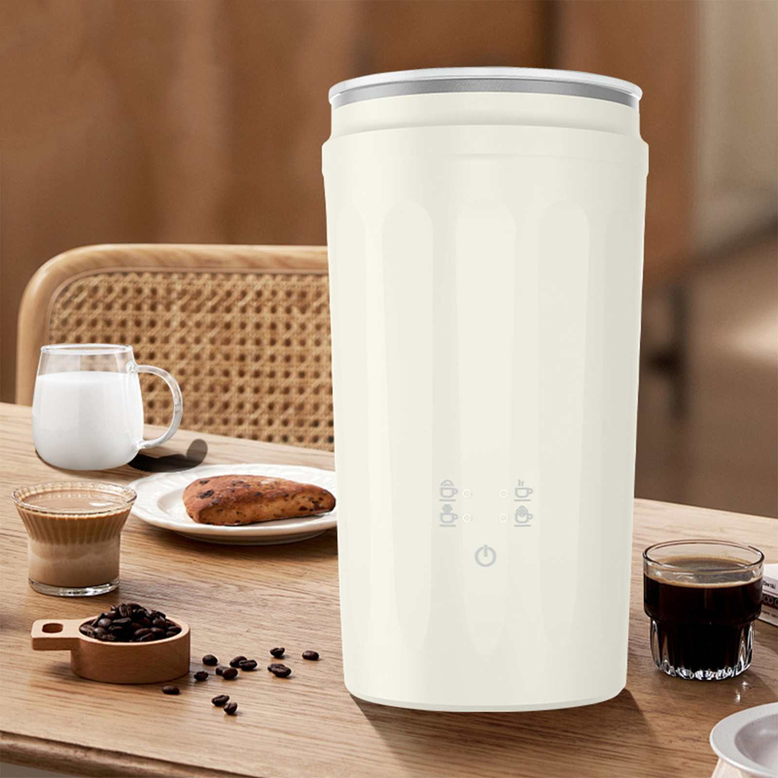 Cremefarbener Kaffeezubereiter, Kaffee, Brot, Milch und Kaffeebohnen auf einem Holztisch, vor verschwommenem Hintergrund.