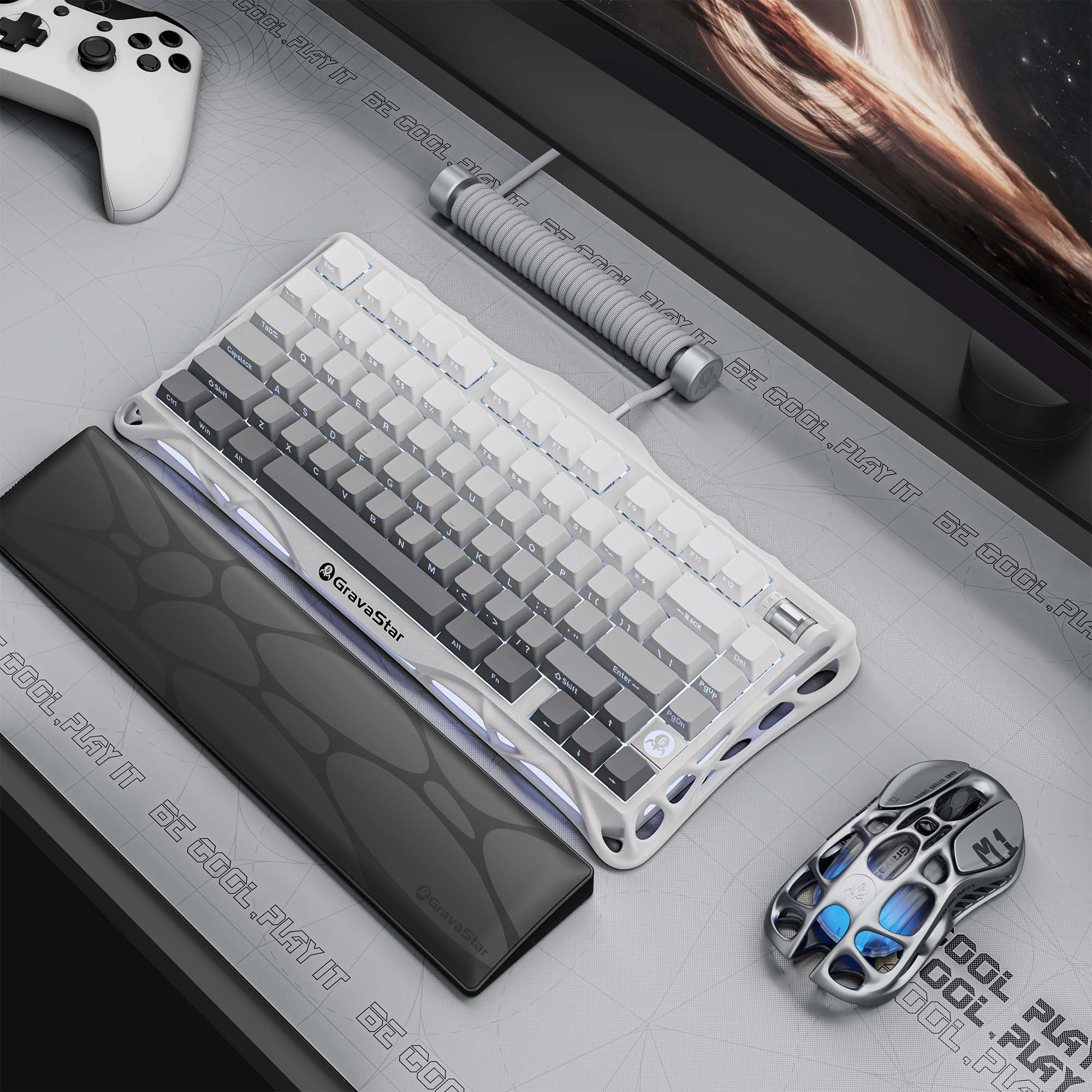 Konfiguracja do gier z białą klawiaturą, myszą i kontrolerem na szarej powierzchni. Czarny monitor w tle.