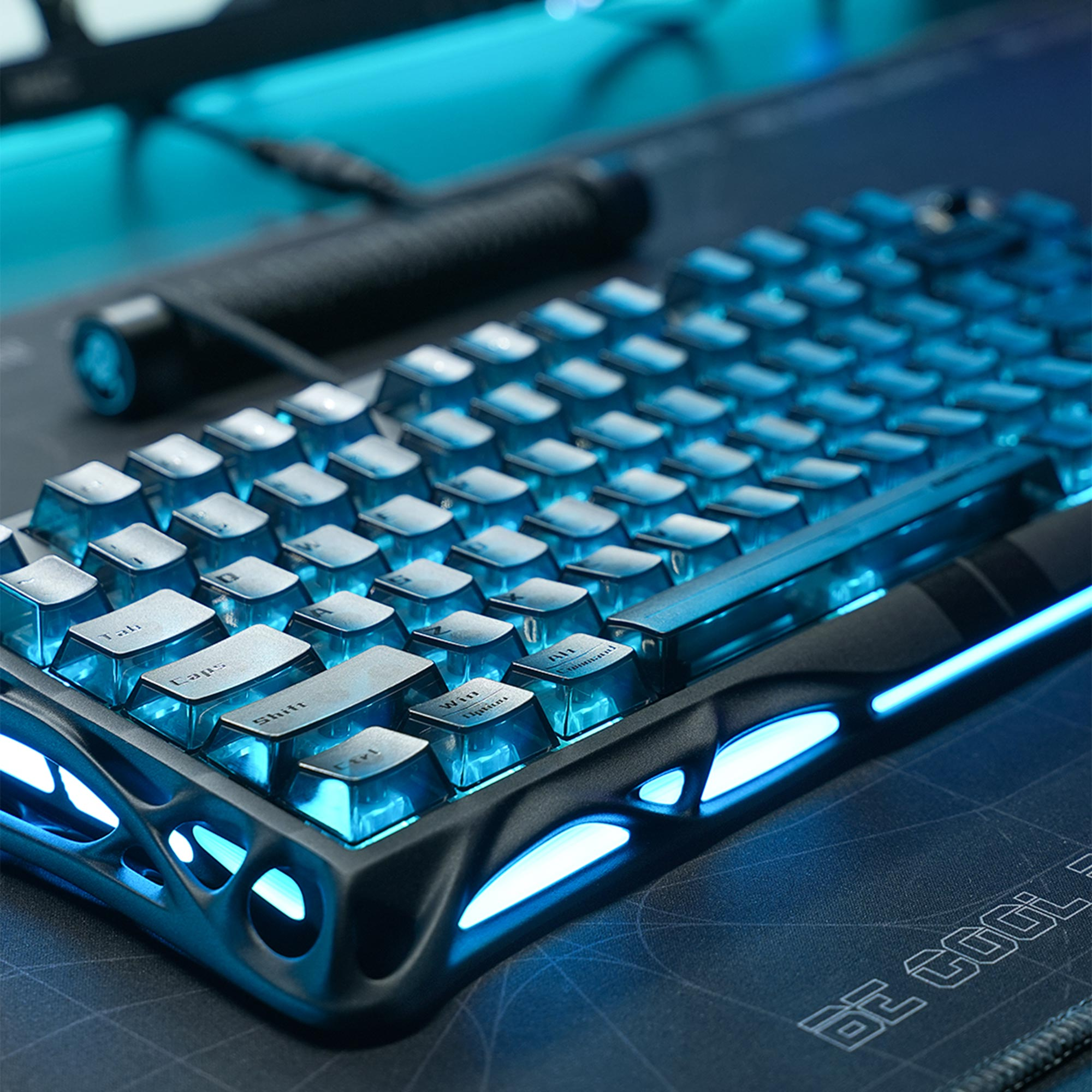 Zbliżenie podświetlanej klawiatury mechanicznej z niebieskimi klawiszami i światłami. Widoczna jest czarna podkładka pod mysz i cylindryczny przedmiot.