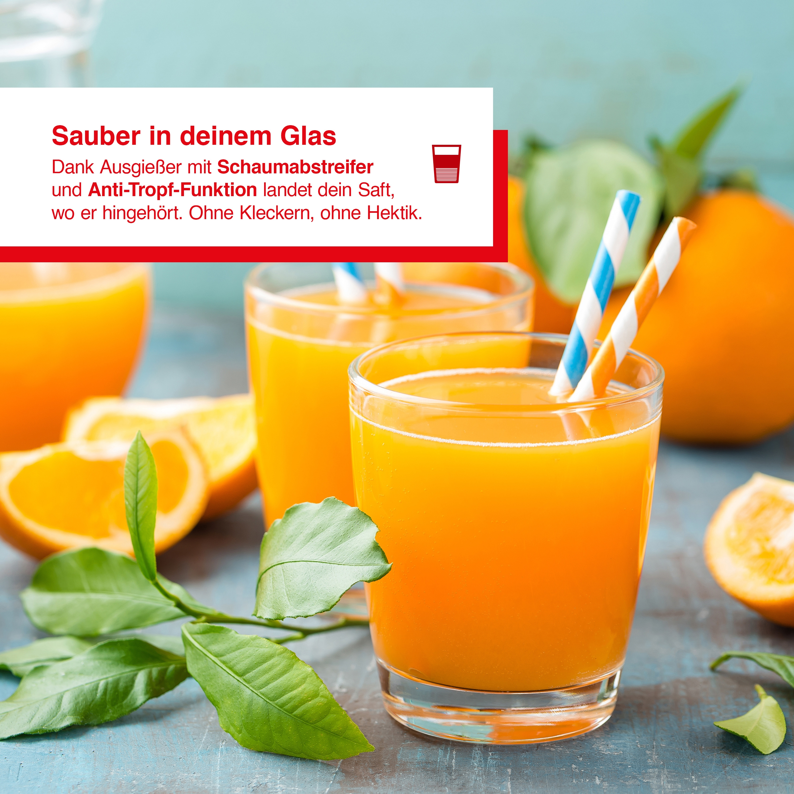 Due bicchieri di succo d'arancia con cannucce, circondati da arance e foglie verdi, su un tavolo blu.