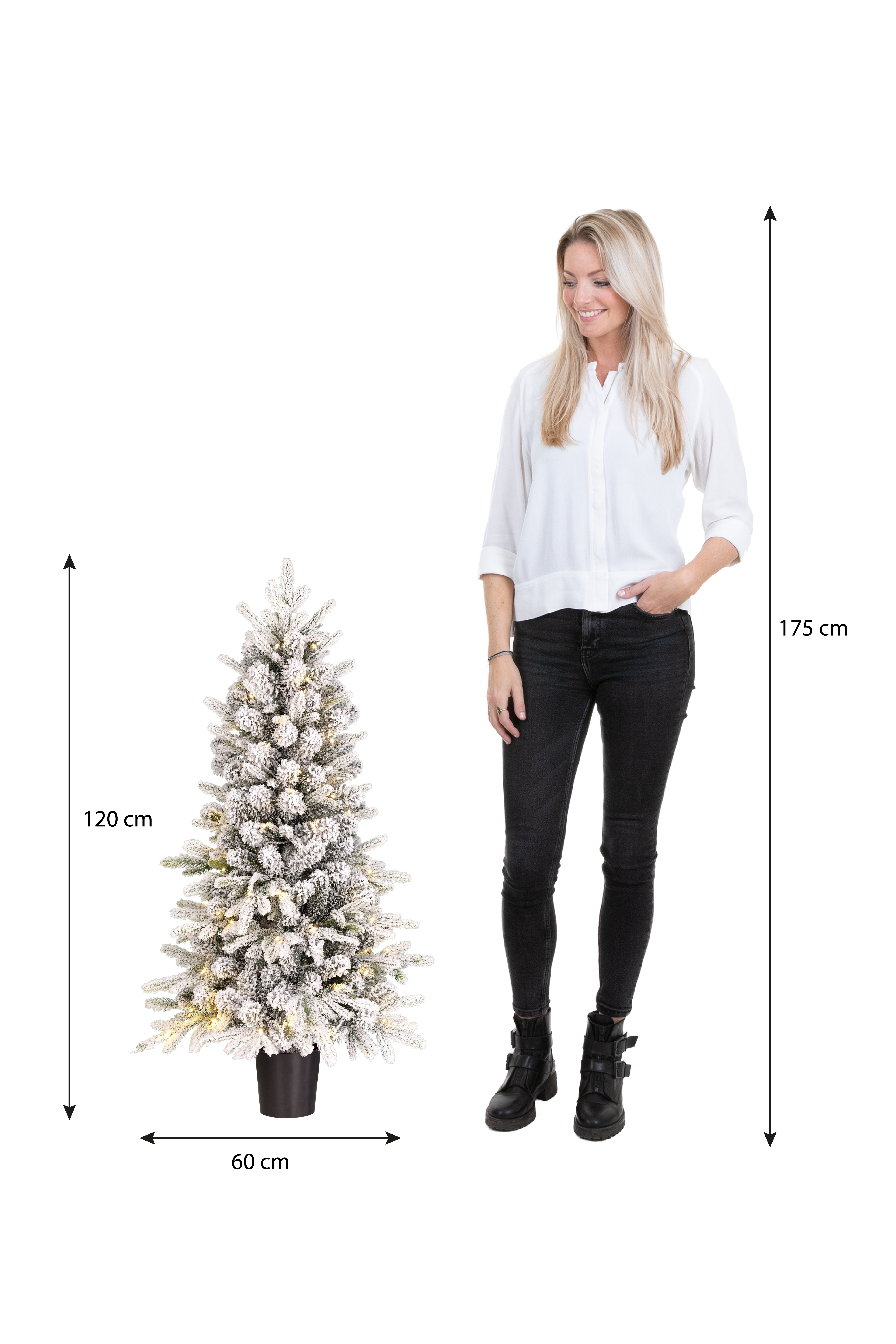 Une femme se tient à côté d'un sapin de Noël floqué de 120 cm. La femme mesure 175 cm et porte une chemise blanche et un pantalon noir.